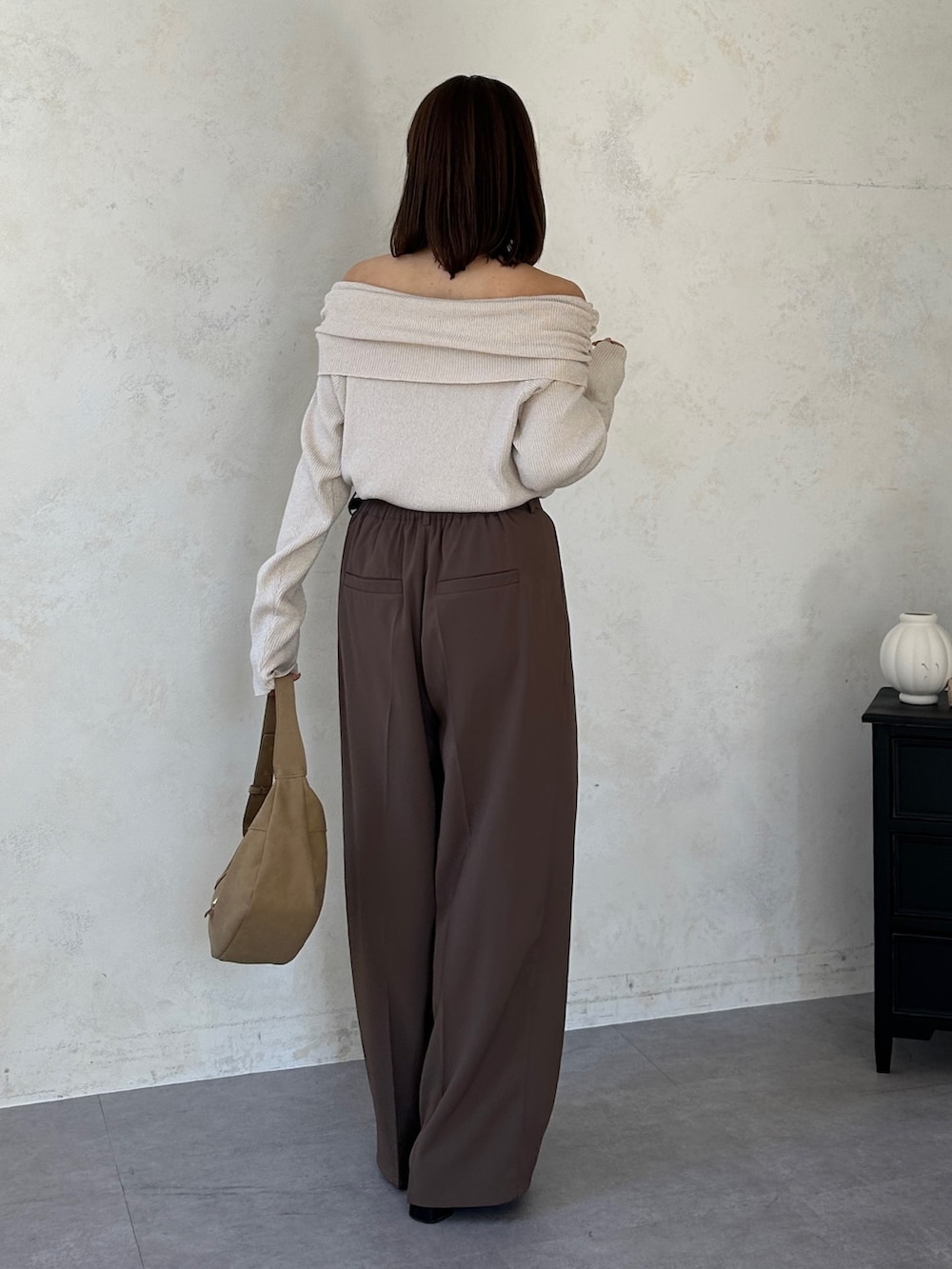 ブラウン系のスラックス、ベージュ系のニット/セーター、ベージュ系のトートバッグを着用したレディースの冬コーディネートの2枚目の写真