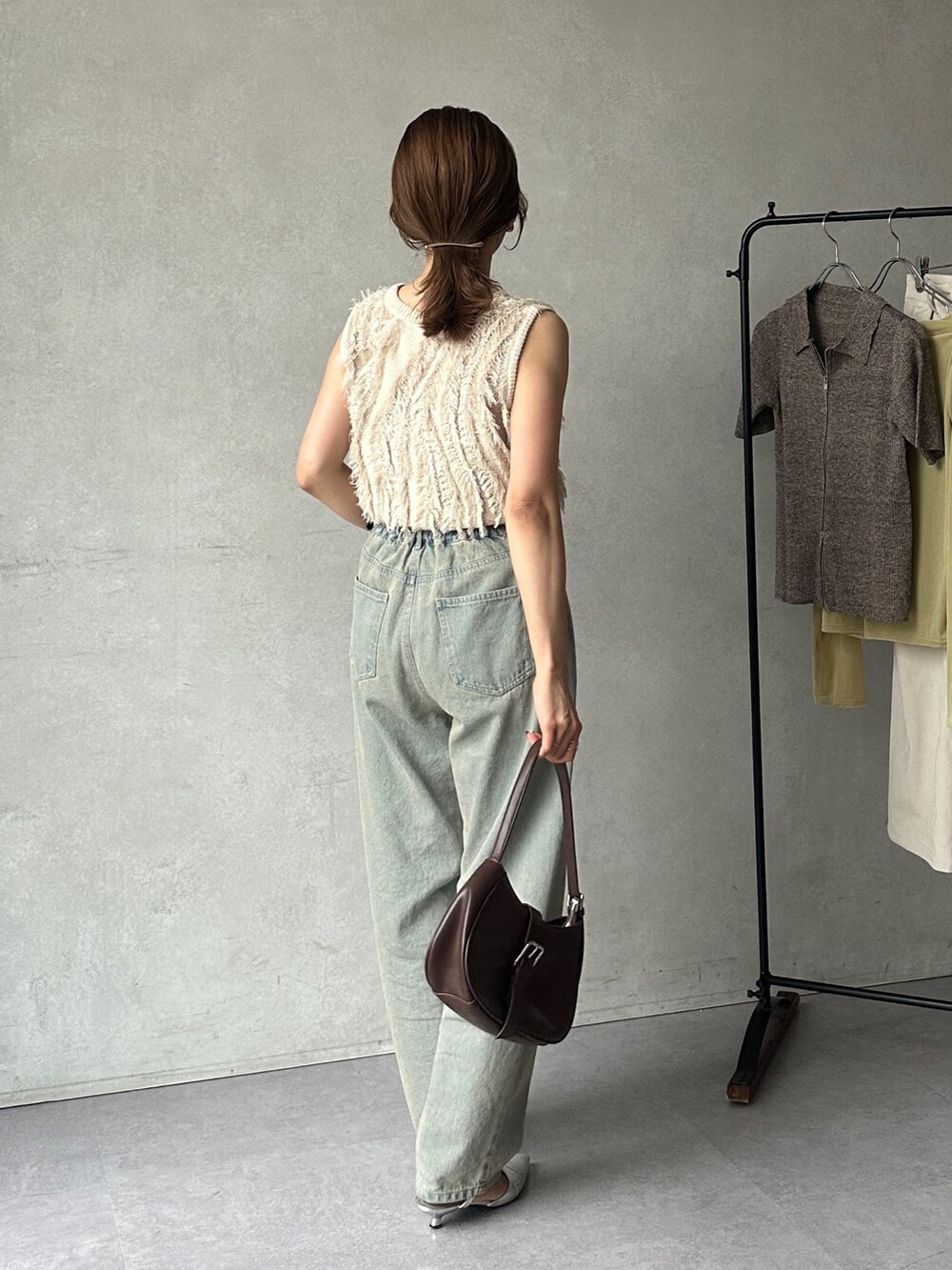 ブルー系のデニムパンツ、ホワイト系のニット/セーター、ブラック系のパンプスを着用したレディースの夏コーディネートの4枚目の写真