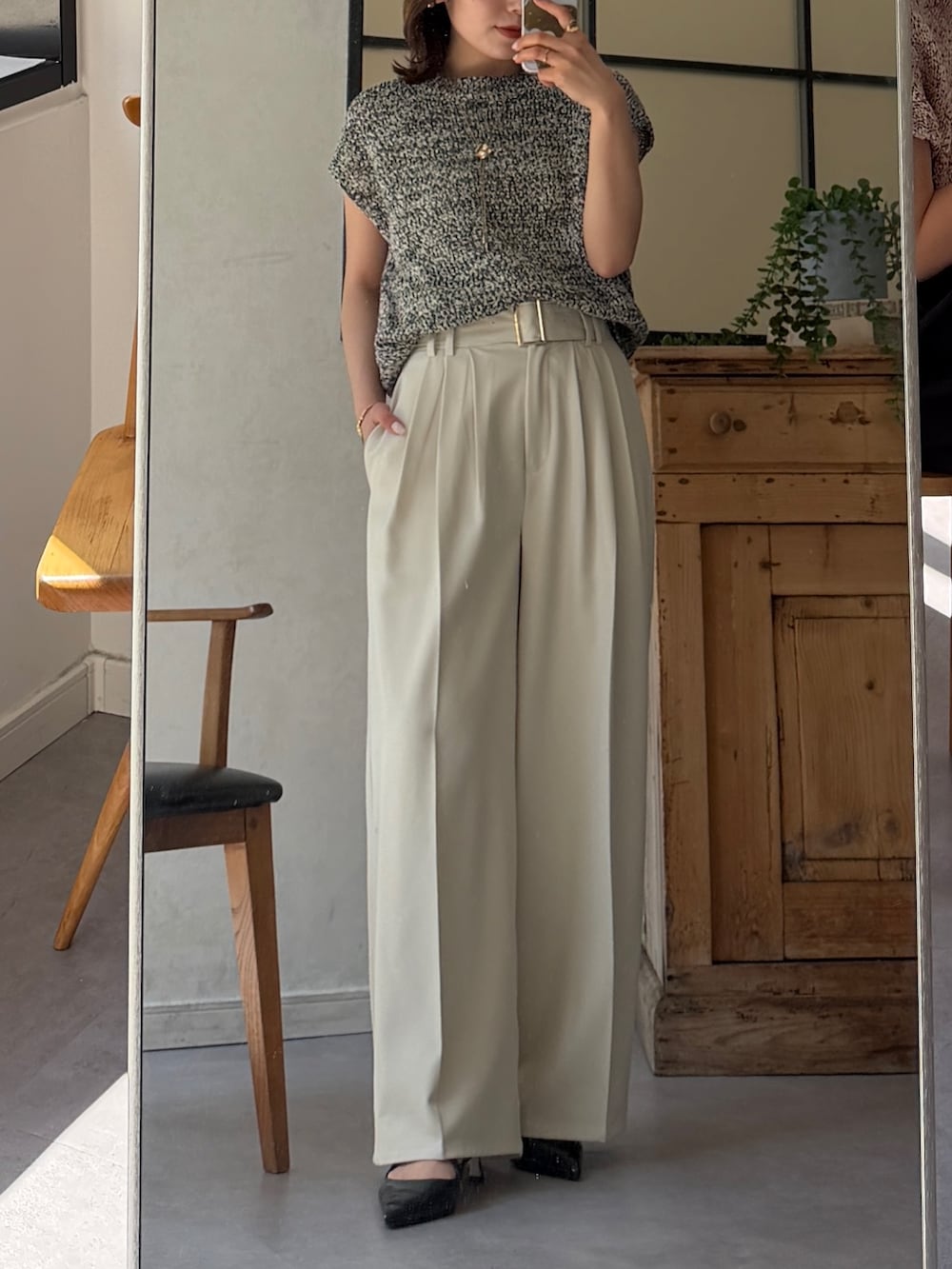 ホワイト系のスラックス、ブラック系のニット/セーター、ブラウン系のパンプスを着用したレディースの春コーディネートの6枚目の写真