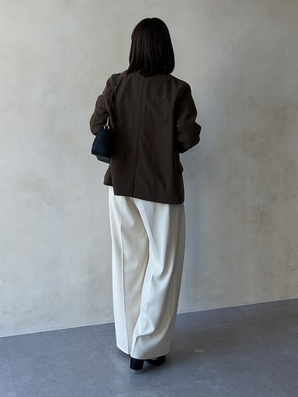 ホワイト系のスラックス、ブラック系のパンプス、ブルー系のニット/セーターを着用したレディースの冬コーディネートの2枚目の写真