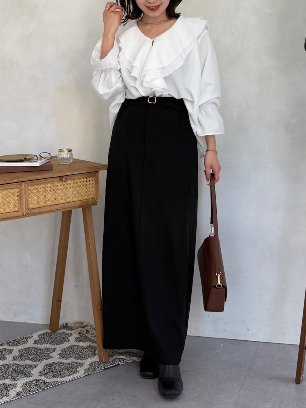 ブラック系のスカート、ブラウン系のショルダーバッグ、ホワイト系のシャツ/ブラウスを着用したレディースの冬コーディネートの5枚目の写真