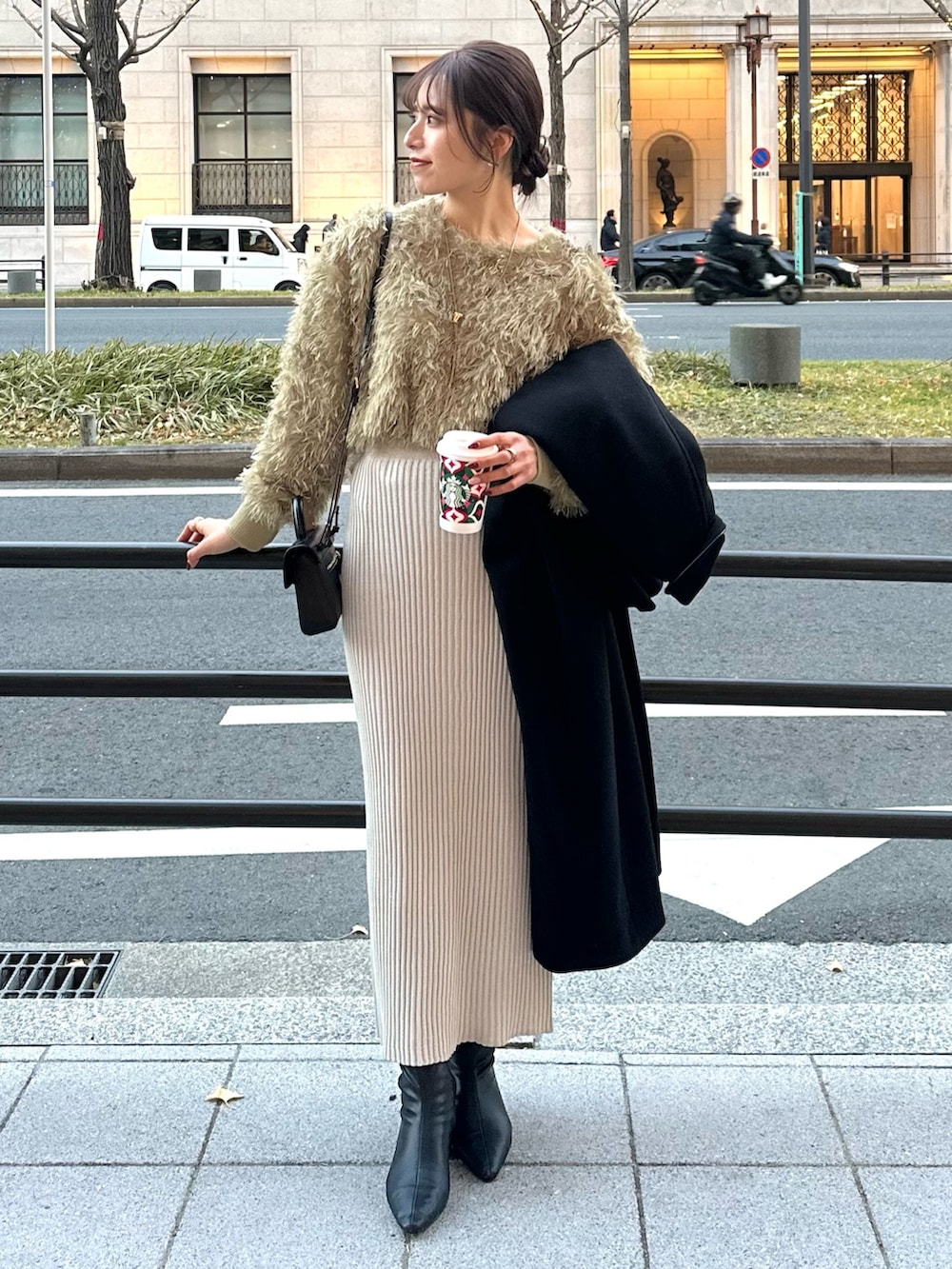 グレー系のスカート、グリーン系のTシャツ/カットソー、ブラック系のステンカラーコートを着用したレディースの冬コーディネートの4枚目の写真