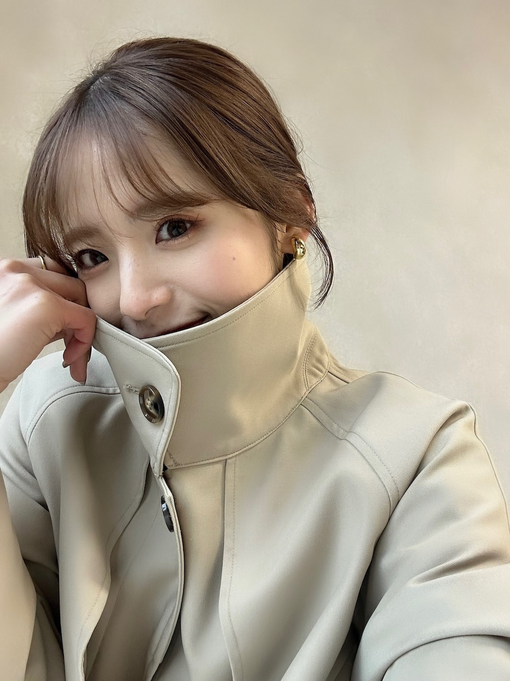 イエロー系のカーディガン/ボレロ、ベージュ系のステンカラーコートを着用したレディースの冬コーディネートの3枚目の写真