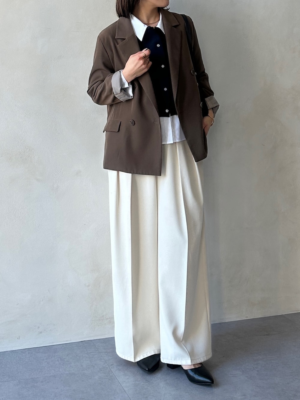 ホワイト系のスラックス、ブラック系のパンプス、ブルー系のニット/セーターを着用したレディースの冬コーディネートの4枚目の写真