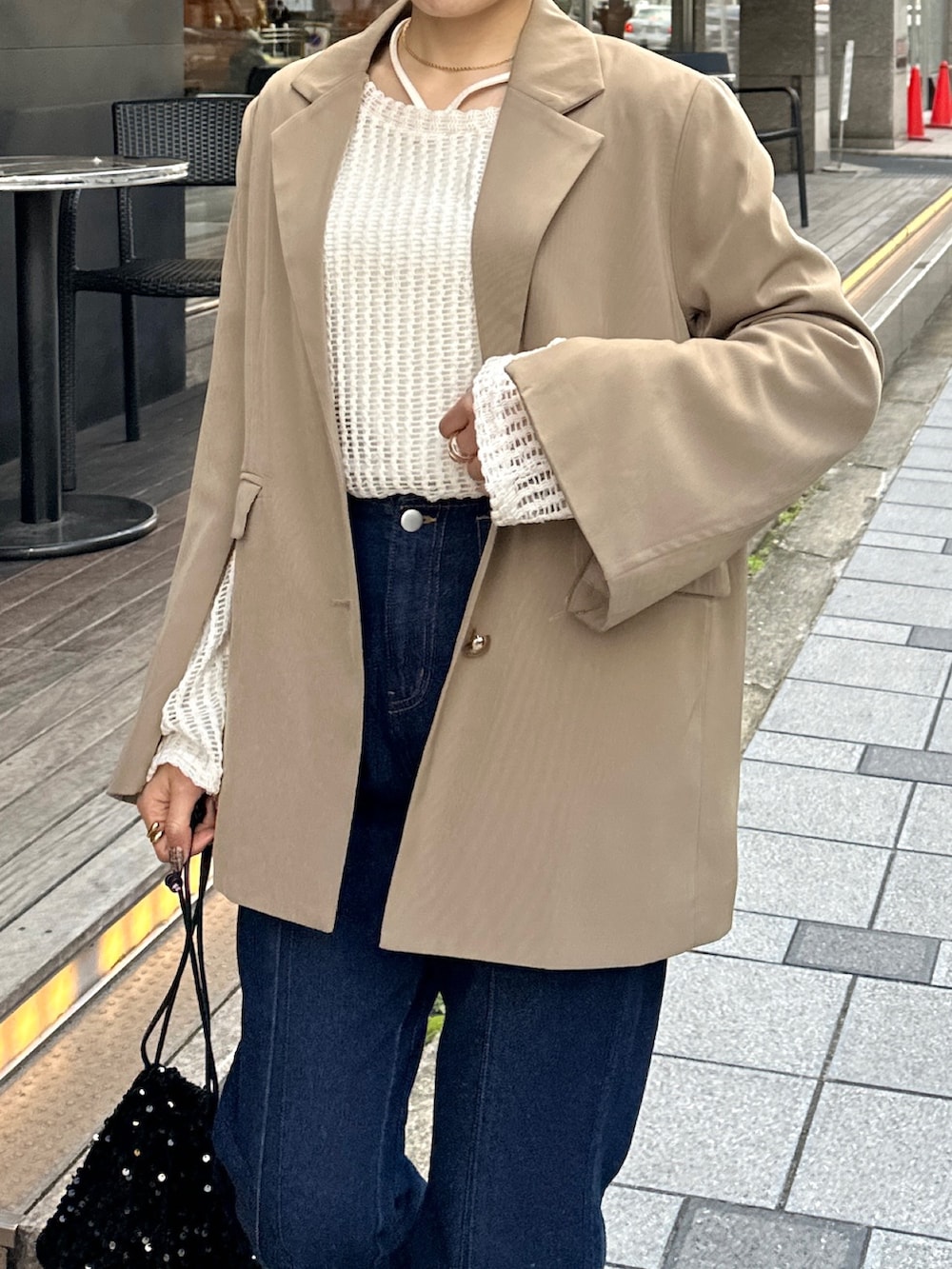 ブルー系のデニムパンツ、ブラック系のトートバッグ、ブラウン系のテーラードジャケットを着用したレディースの春コーディネートの5枚目の写真