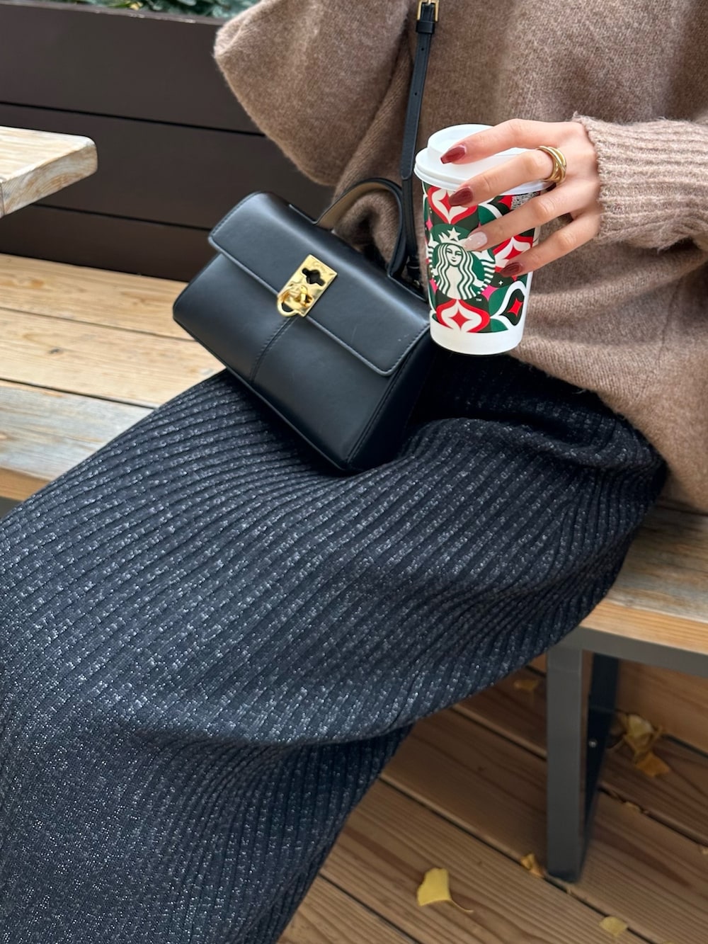 イエロー系のニット/セーター、ブラック系のスカート、ブラック系のブーツを着用したレディースの冬コーディネートの4枚目の写真
