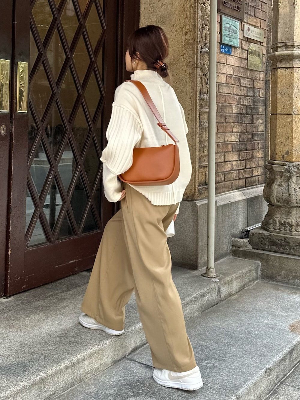 ベージュ系のスラックス、ホワイト系のニット/セーター、ブラウン系のショルダーバッグを着用したレディースの秋コーディネートの3枚目の写真