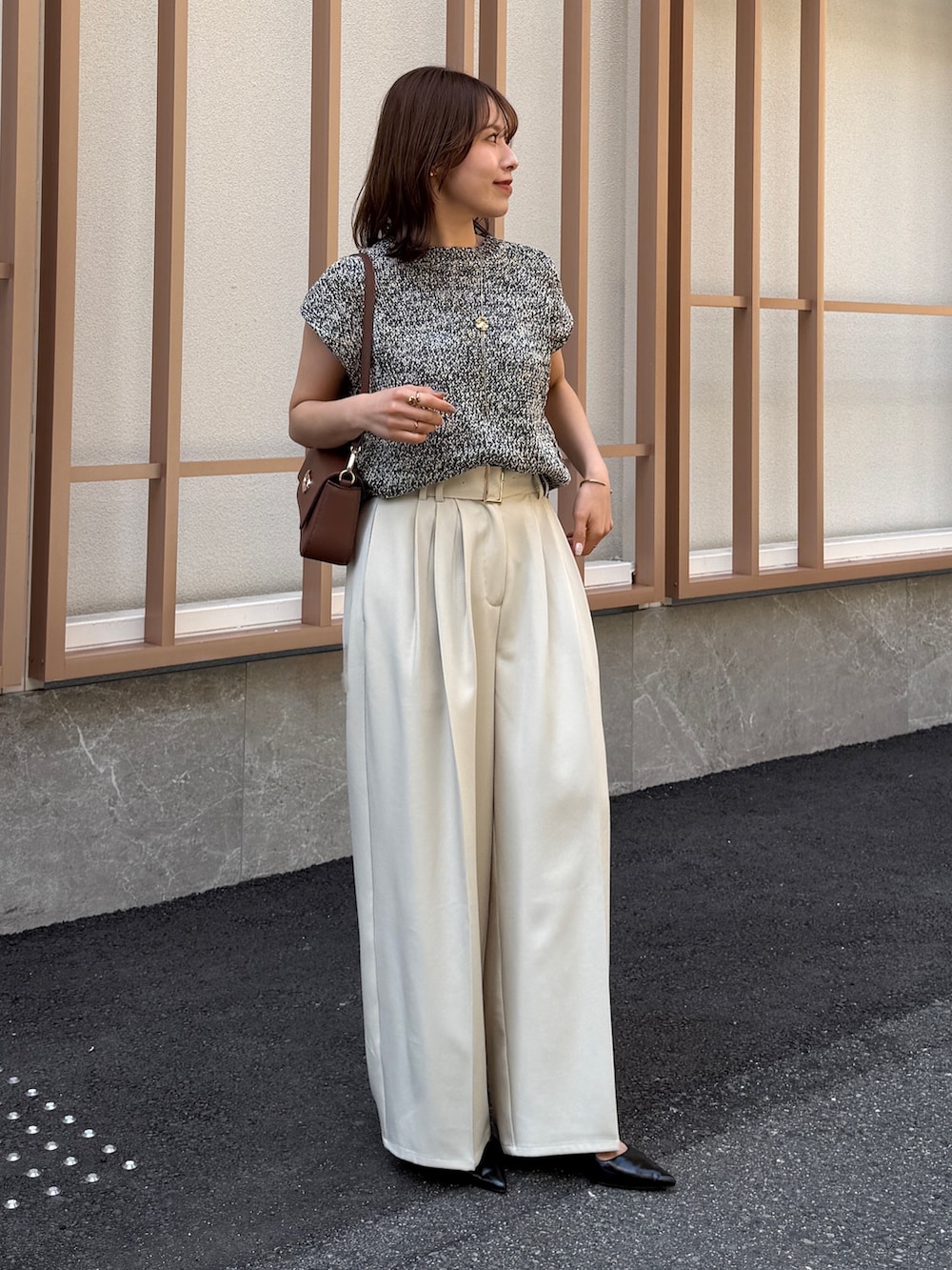 ホワイト系のスラックス、ブラック系のニット/セーター、ブラウン系のパンプスを着用したレディースの春コーディネートの5枚目の写真