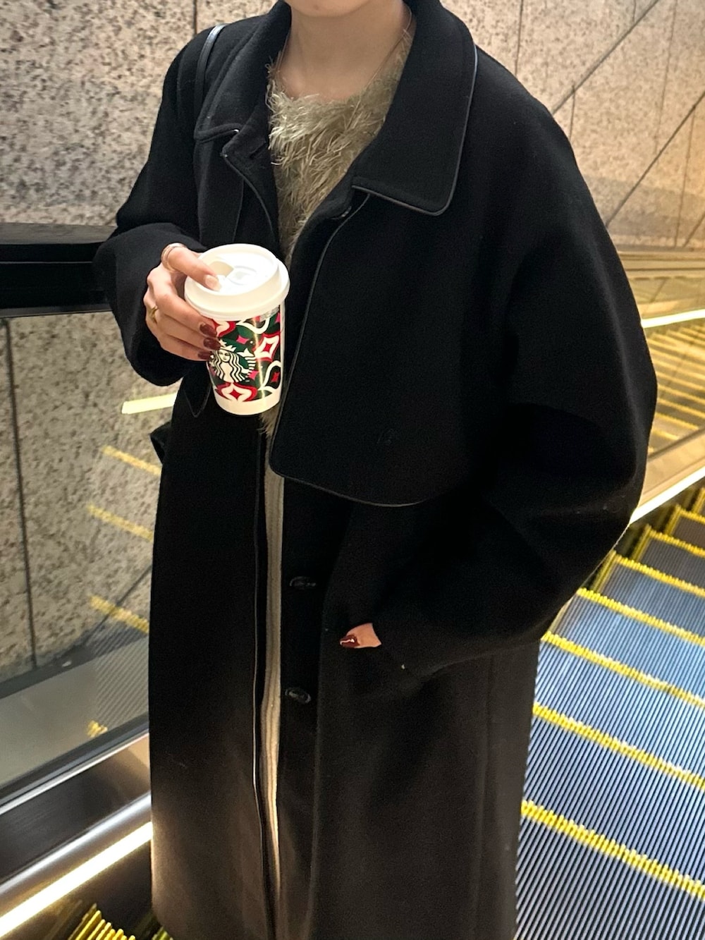 グレー系のスカート、グリーン系のTシャツ/カットソー、ブラック系のステンカラーコートを着用したレディースの冬コーディネートの7枚目の写真