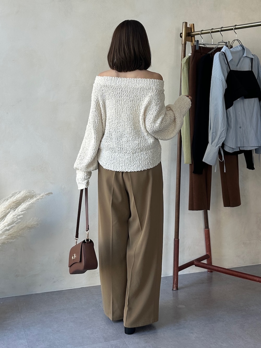 イエロー系のスラックス、ブラック系のパンプス、ホワイト系のニット/セーターを着用したレディースの冬コーディネートの3枚目の写真