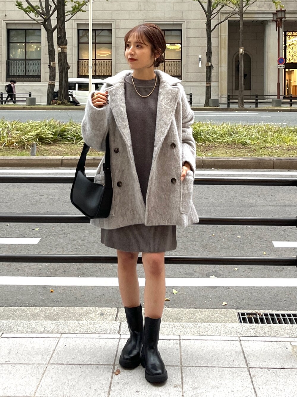 グレー系のピーコート、グレー系のワンピース、ブラック系のブーツを着用したレディースの秋コーディネートの4枚目の写真