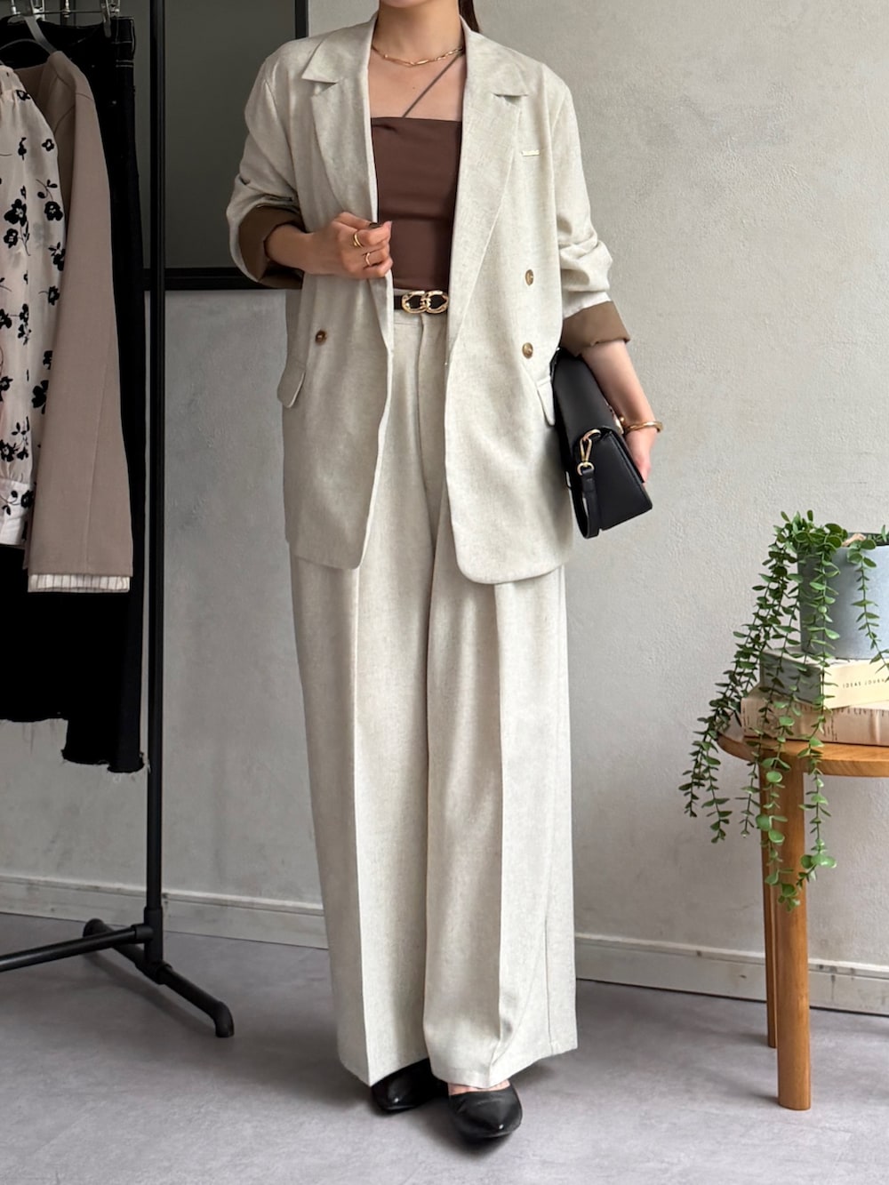 ベージュ系のテーラードジャケット、ホワイト系のスラックス、ブラック系のパンプスを着用したレディースの春コーディネートの2枚目の写真