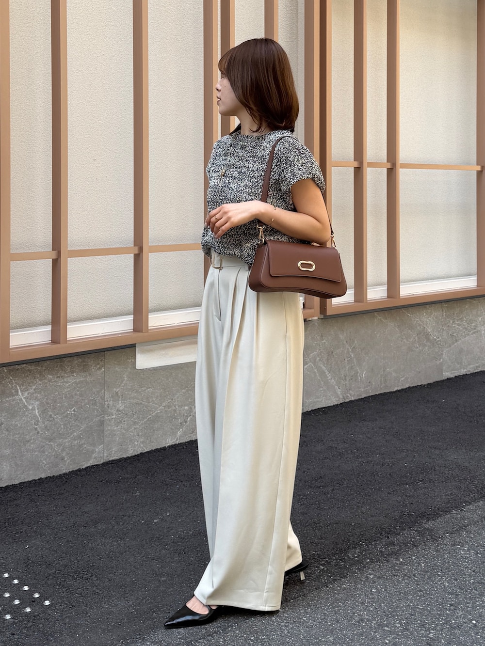 ホワイト系のスラックス、ブラック系のニット/セーター、ブラウン系のパンプスを着用したレディースの春コーディネートの3枚目の写真