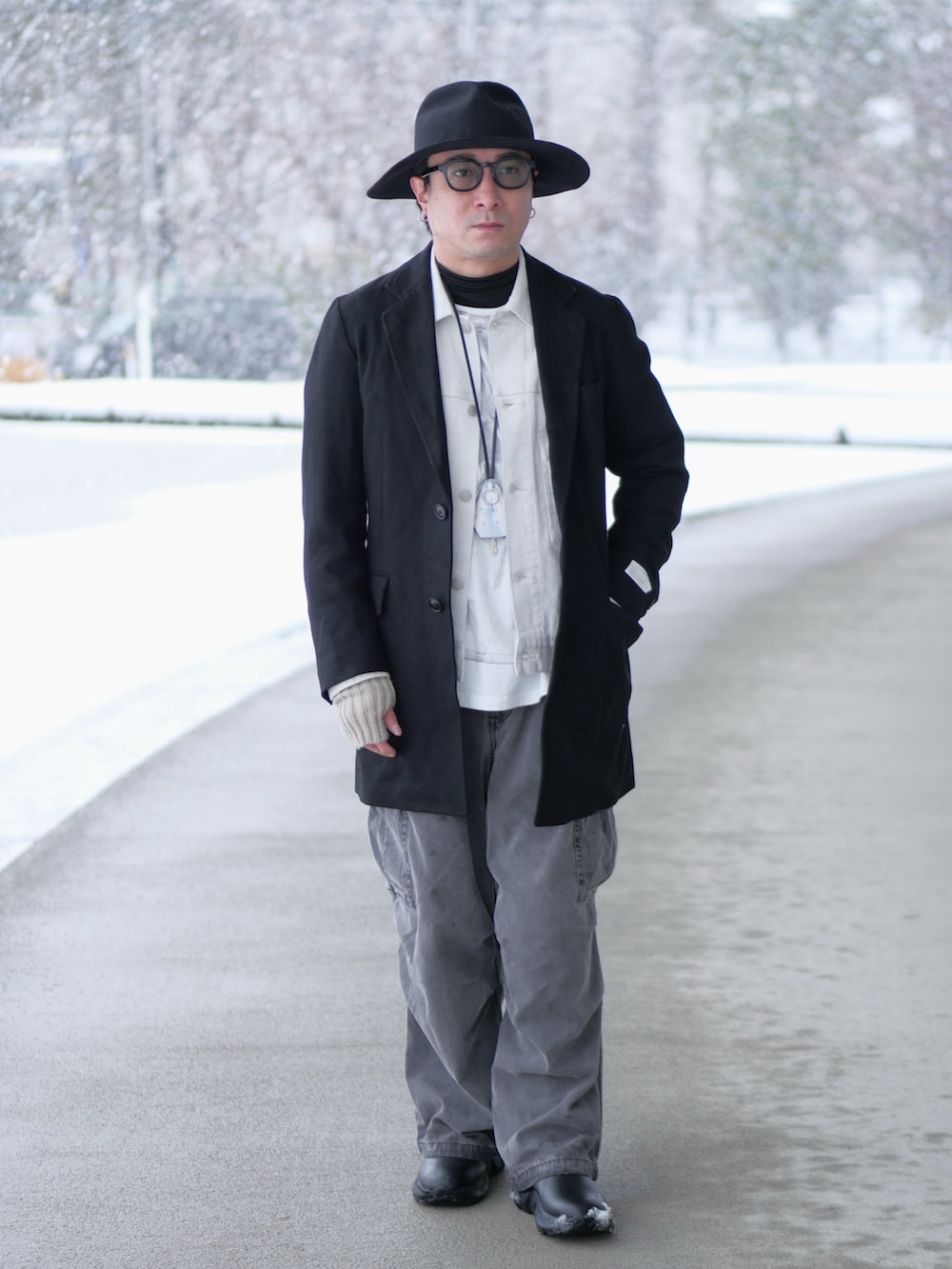 ブラック系のチェスターコート、ホワイト系のデニムジャケット、ホワイト系のTシャツ/カットソーを着用したメンズの冬コーディネートの2枚目の写真