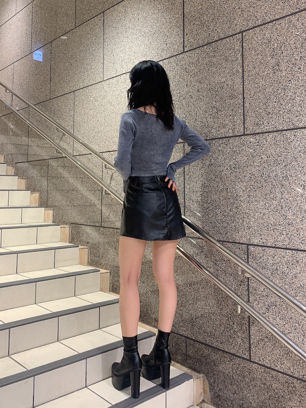 ブラック系のスカート、ブルー系のニット/セーター、ブラック系のブーツを着用したレディースの秋コーディネートの2枚目の写真