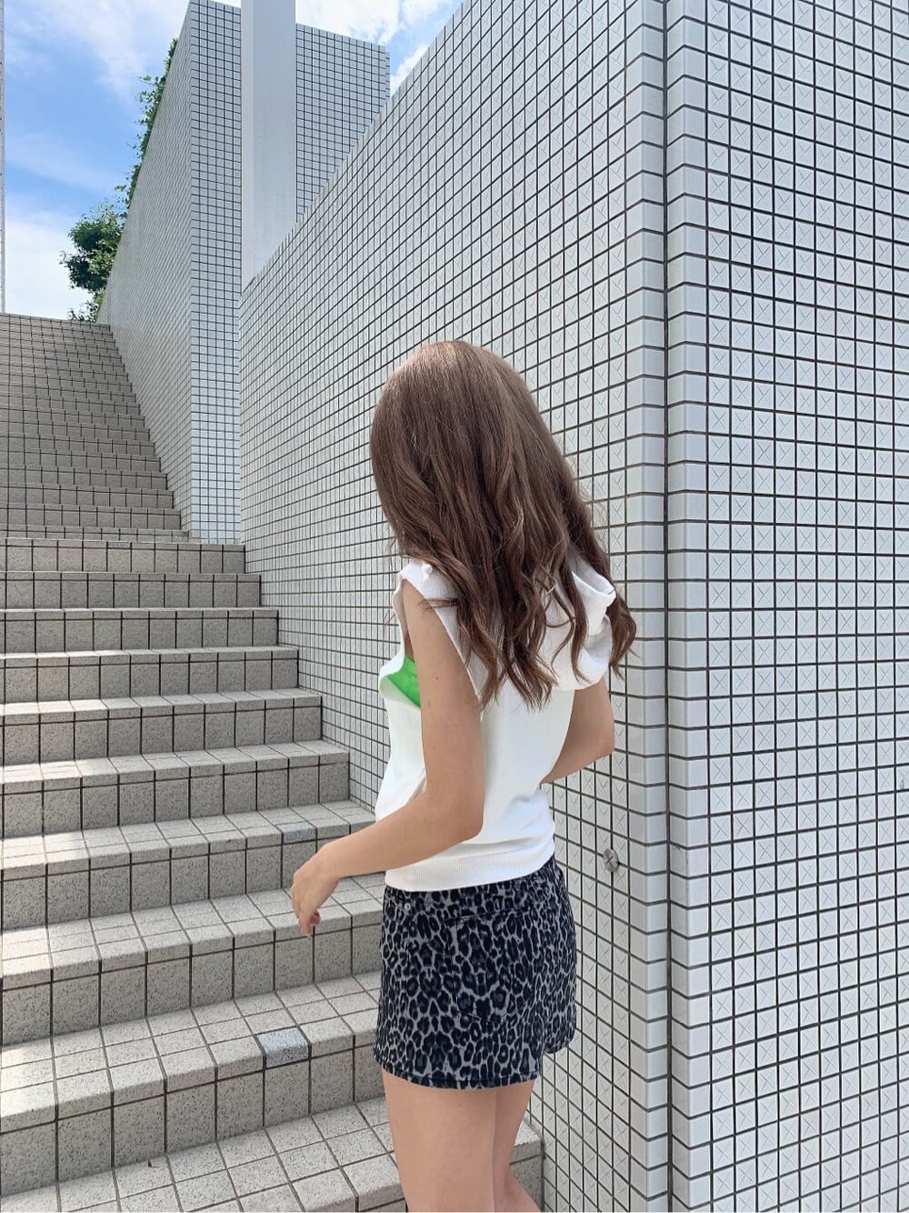 グレー系のスカート、ブラック系のサンダル、ホワイト系のタンクトップを着用したレディースの夏コーディネートの6枚目の写真