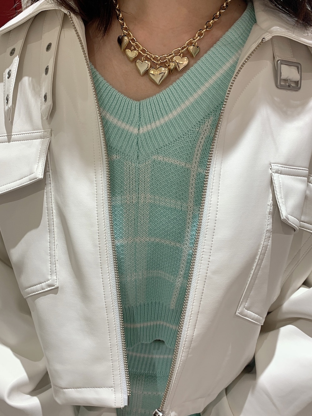 グリーン系のスカート、グリーン系のニット/セーター、ホワイト系のライダースジャケットを着用したレディースの冬コーディネートの7枚目の写真