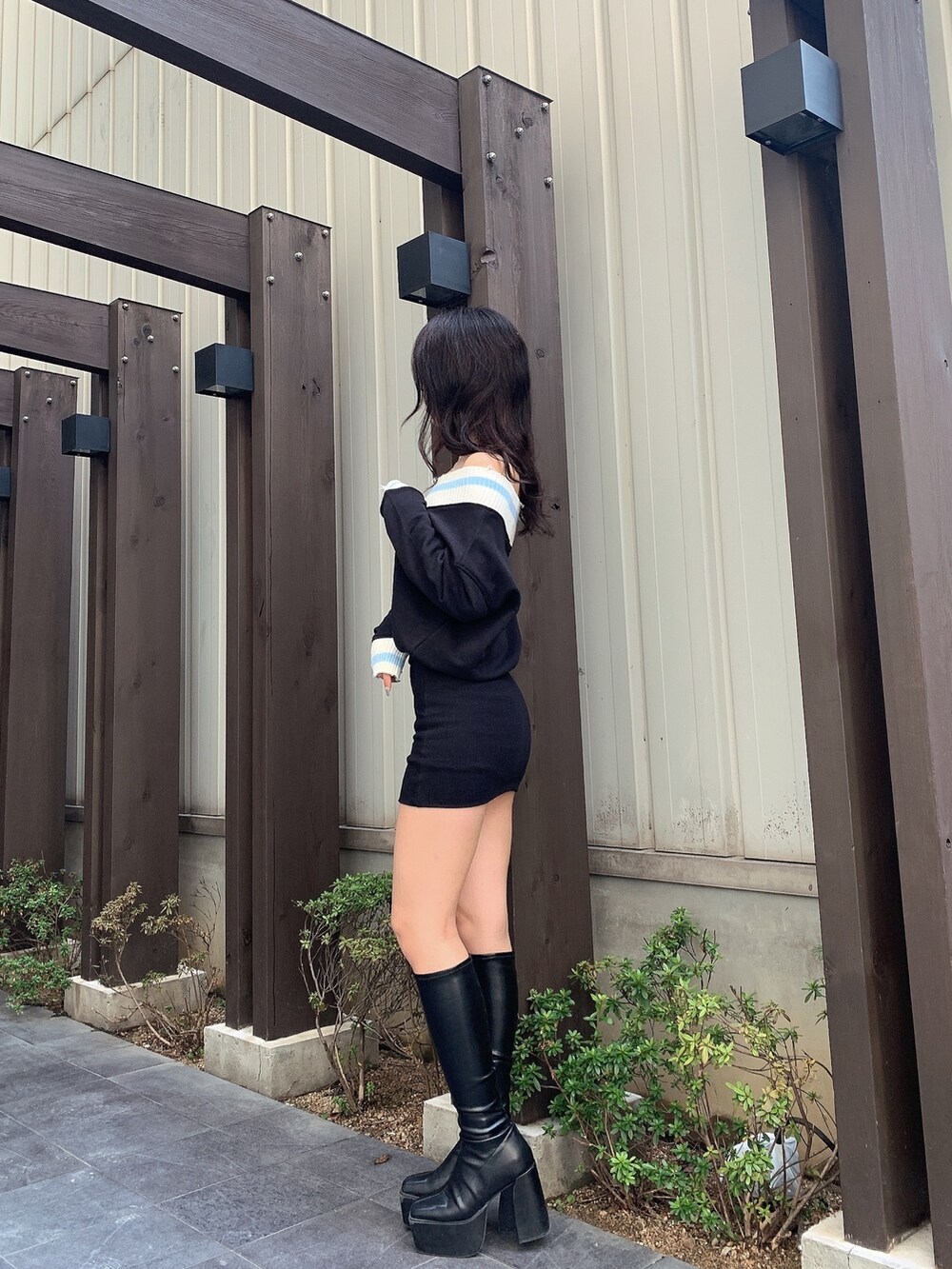 ブラック系のワンピース、ブラック系のブーツを着用したレディースの春コーディネートの2枚目の写真