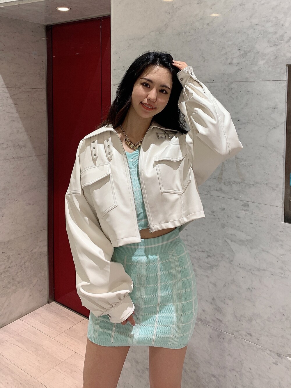 グリーン系のスカート、グリーン系のニット/セーター、ホワイト系のライダースジャケットを着用したレディースの冬コーディネートの4枚目の写真