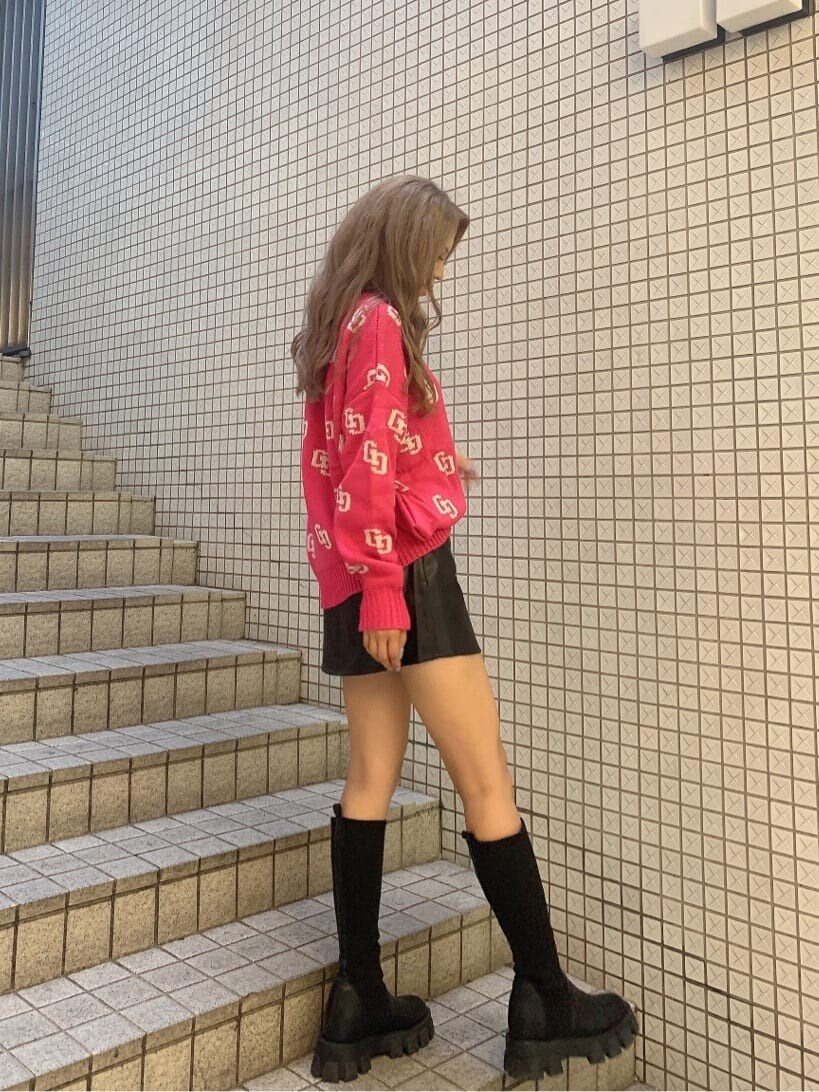 ピンク系のニット/セーター、ブラック系のスカート、ブラック系のブーツを着用したレディースの秋コーディネートの2枚目の写真