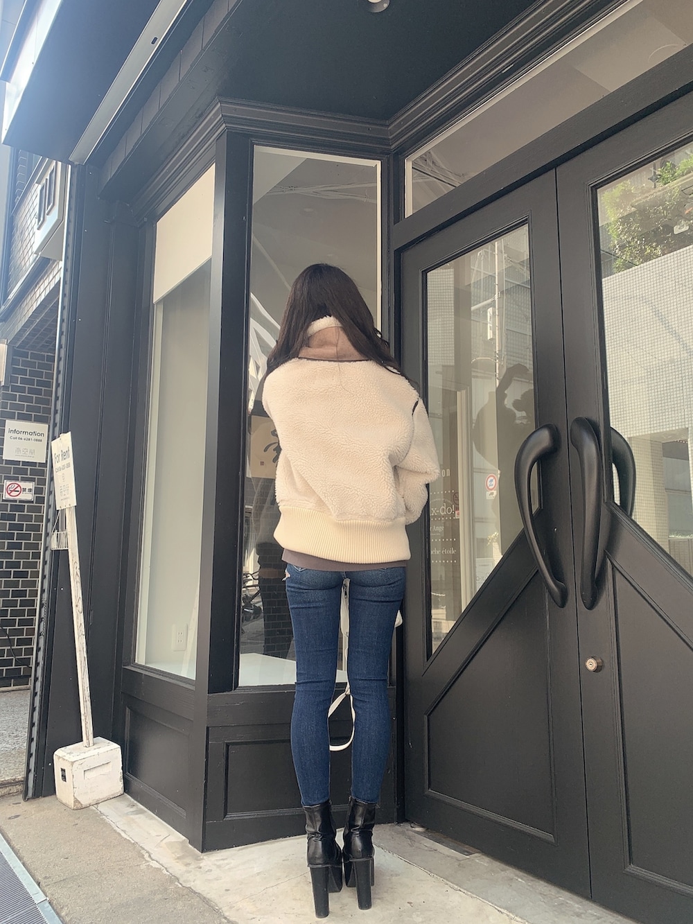 ブルー系のデニムパンツ、ブラック系のブーツ、ホワイト系のバックパック/リュックを着用したレディースの冬コーディネートの2枚目の写真