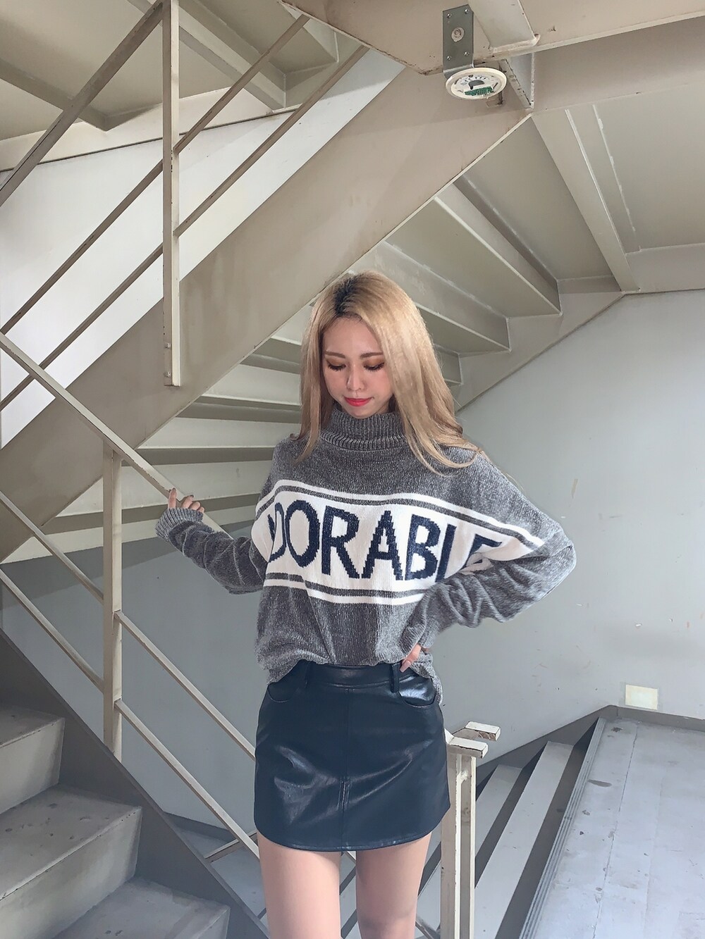 グレー系のニット/セーター、ブラック系のスカート、ブラック系のブーツを着用したレディースの秋コーディネートの5枚目の写真