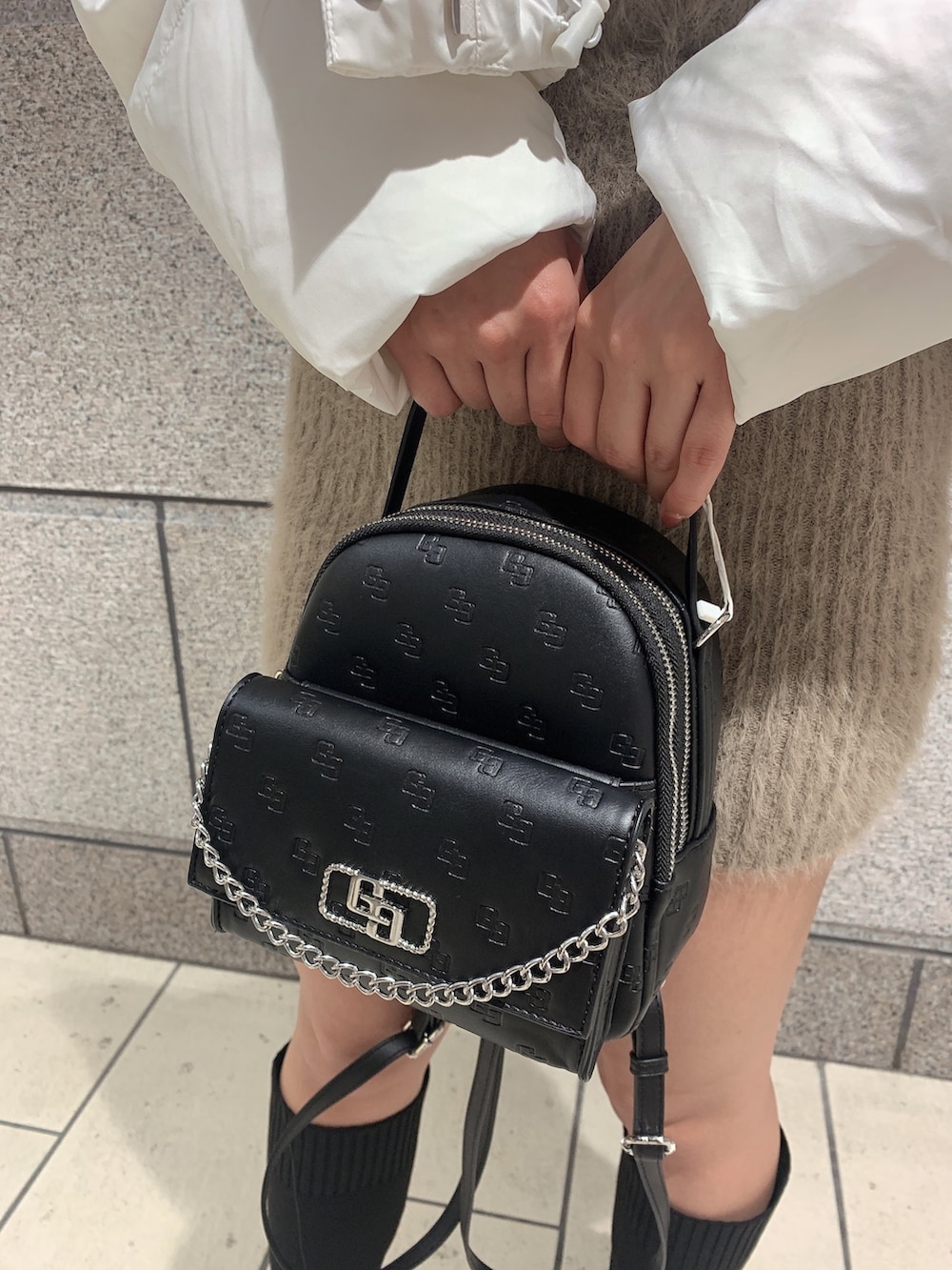 ブラック系のバックパック/リュック、ブラック系のブーツ、ホワイト系のダウンジャケット/コートを着用したレディースの冬コーディネートの9枚目の写真