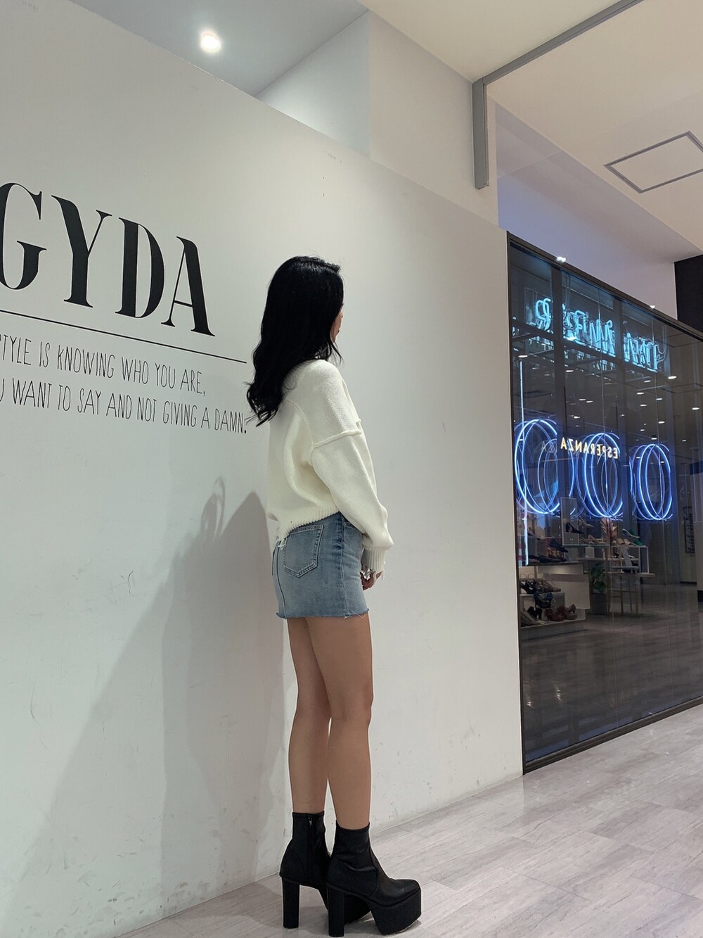 ブルー系のスカート、ブラック系のブーツ、ホワイト系のニット/セーターを着用したレディースの冬コーディネートの2枚目の写真