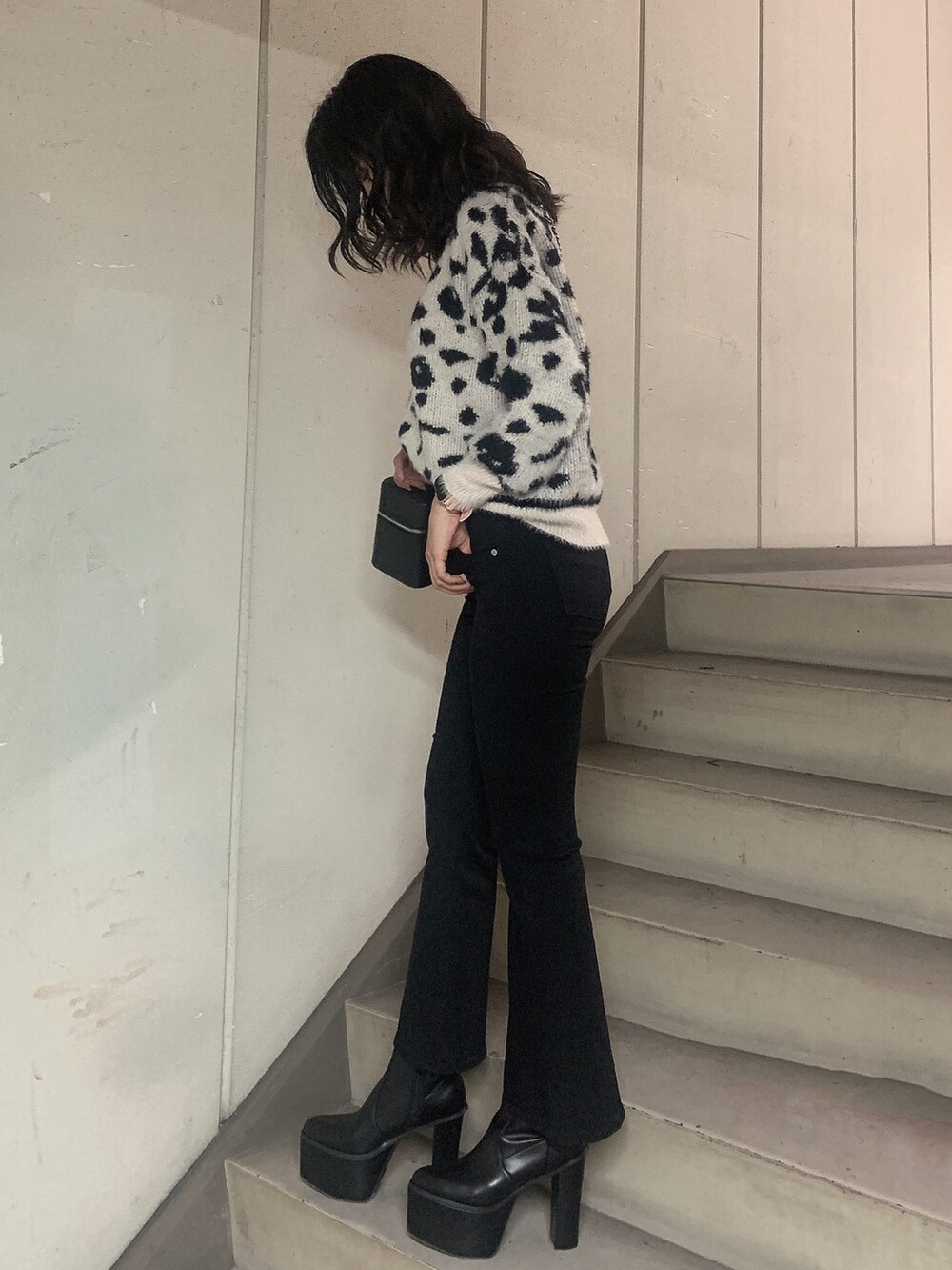 ブラック系のブーツ、ブラック系のデニムパンツ、ホワイト系のニット/セーターを着用したレディースの冬コーディネートの2枚目の写真