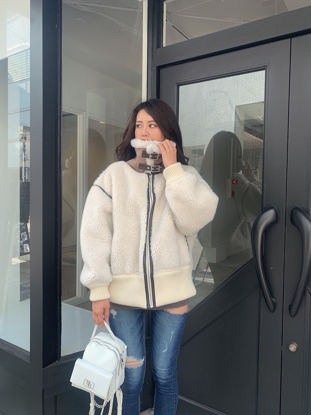 ブルー系のデニムパンツ、ブラック系のブーツ、ホワイト系のバックパック/リュックを着用したレディースの冬コーディネートの4枚目の写真