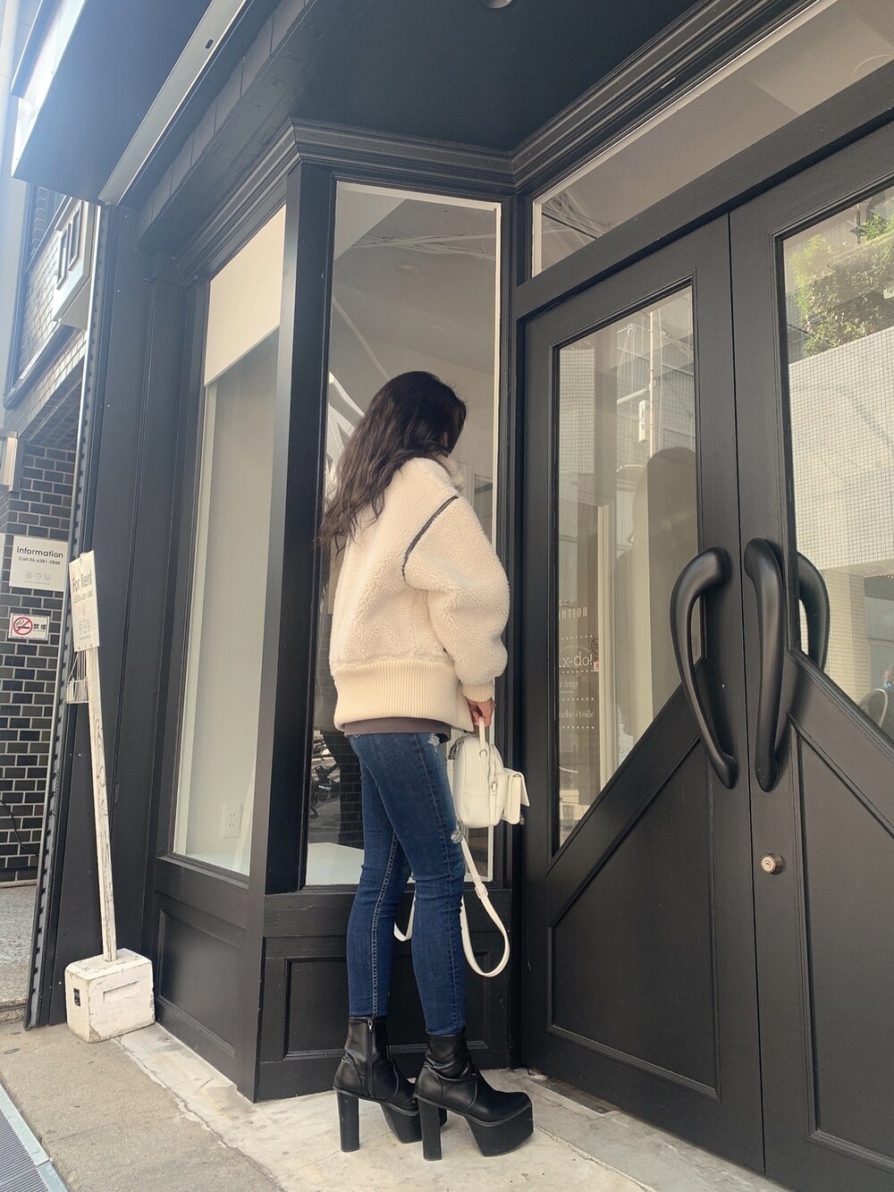 ブルー系のデニムパンツ、ブラック系のブーツ、ホワイト系のバックパック/リュックを着用したレディースの冬コーディネートの3枚目の写真