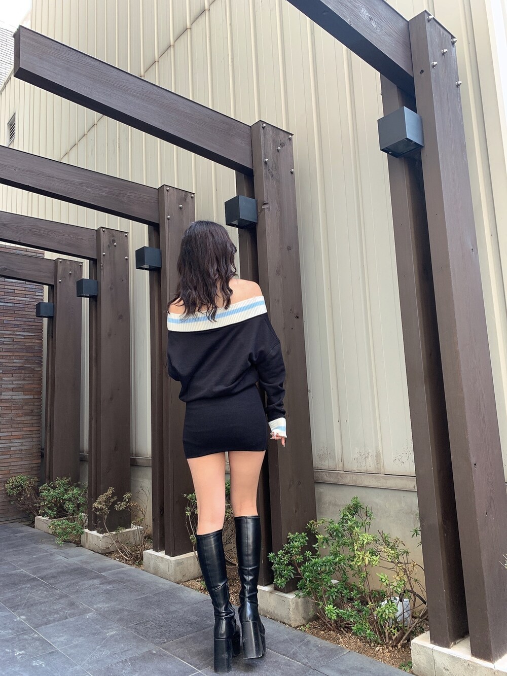 ブラック系のワンピース、ブラック系のブーツを着用したレディースの春コーディネートの3枚目の写真