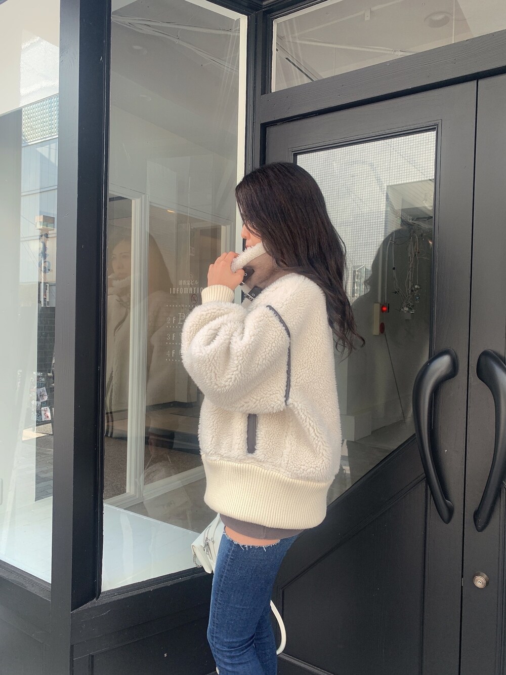 ブルー系のデニムパンツ、ブラック系のブーツ、ホワイト系のバックパック/リュックを着用したレディースの冬コーディネートの6枚目の写真