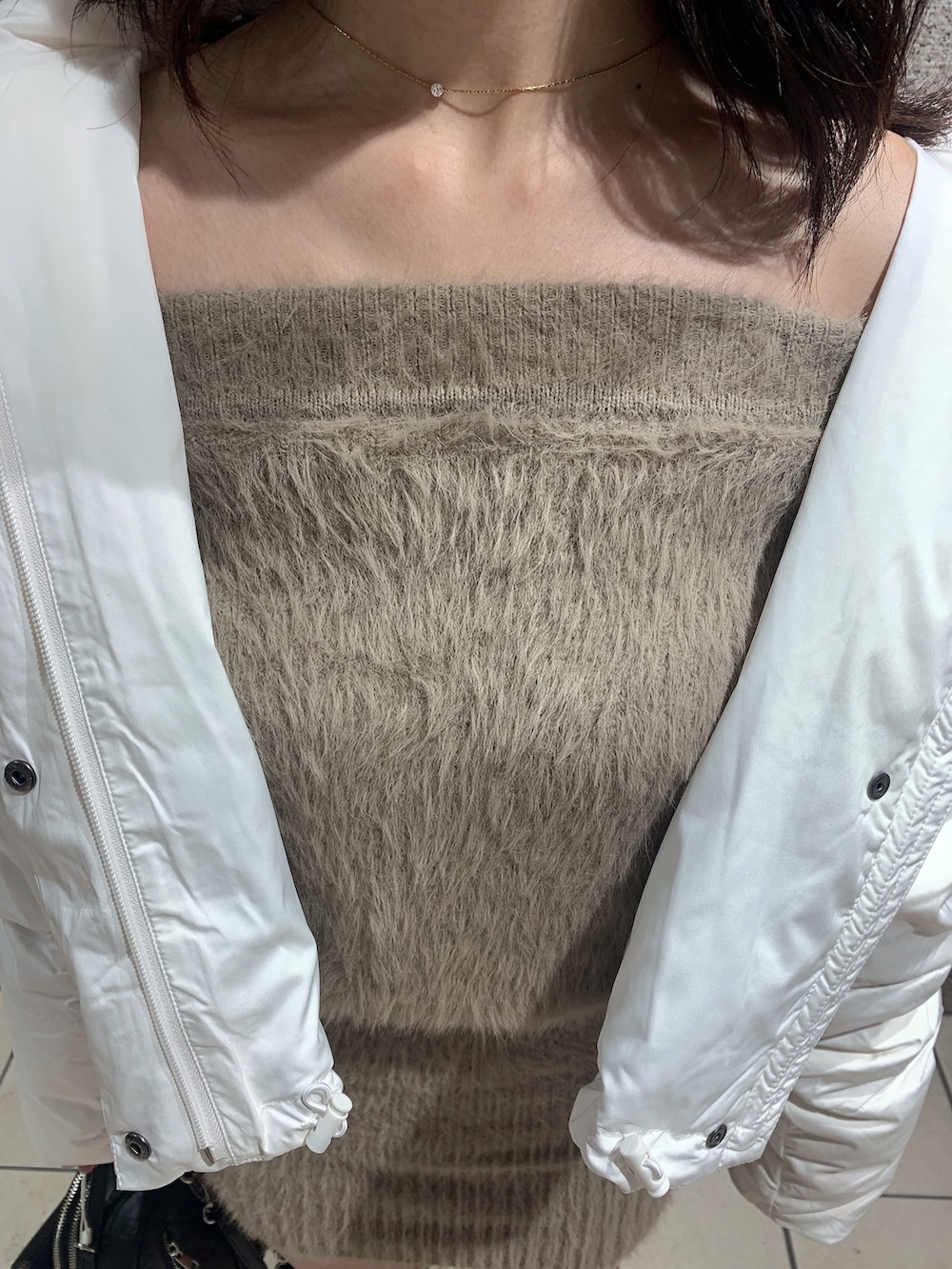 ブラック系のバックパック/リュック、ブラック系のブーツ、ホワイト系のダウンジャケット/コートを着用したレディースの冬コーディネートの6枚目の写真