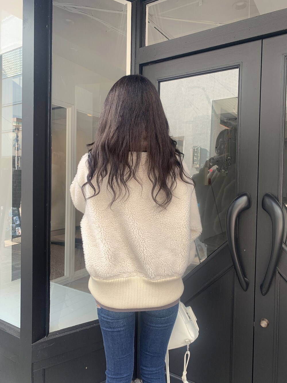 ブルー系のデニムパンツ、ブラック系のブーツ、ホワイト系のバックパック/リュックを着用したレディースの冬コーディネートの5枚目の写真