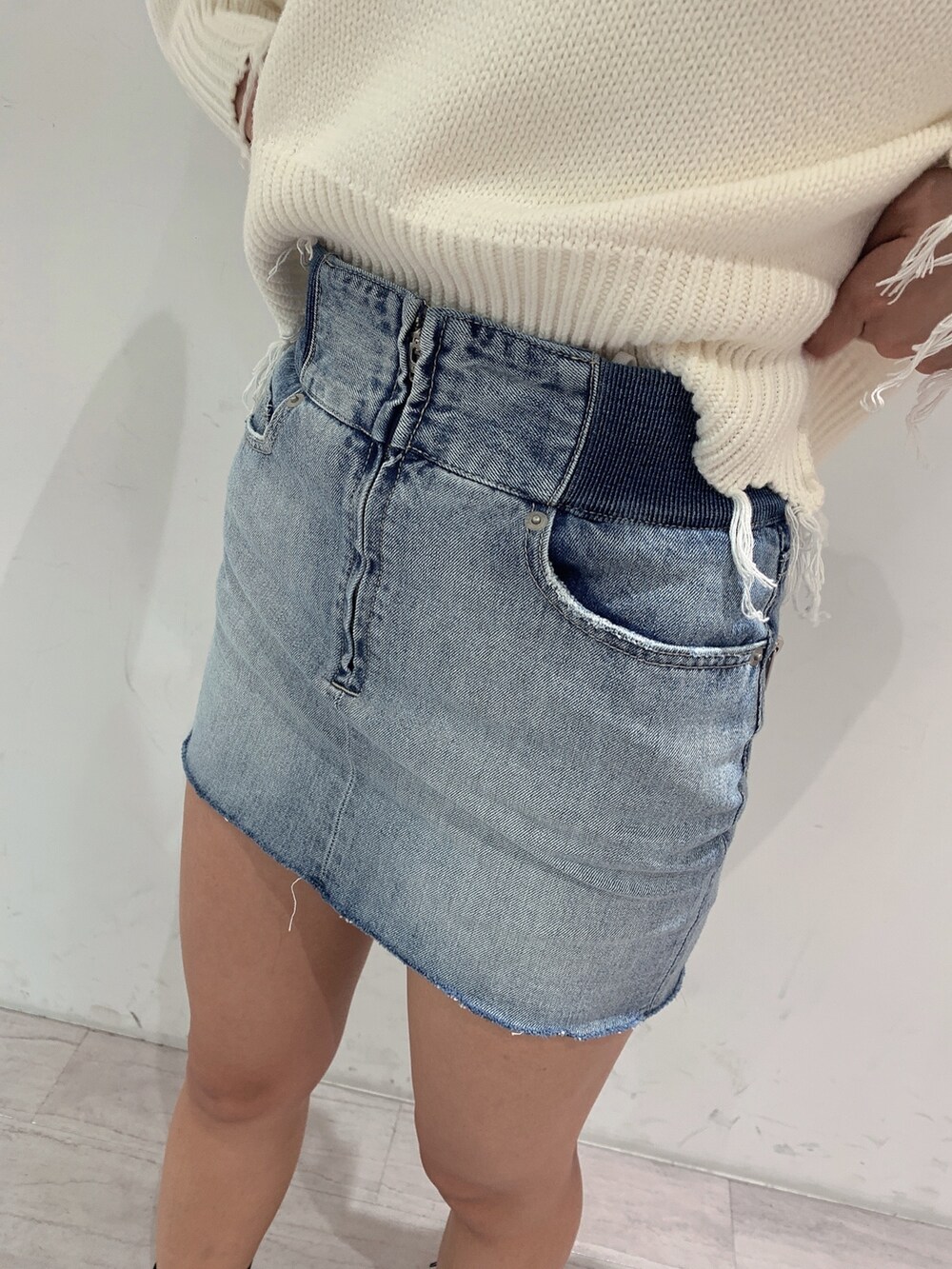 ブルー系のスカート、ブラック系のブーツ、ホワイト系のニット/セーターを着用したレディースの冬コーディネートの8枚目の写真