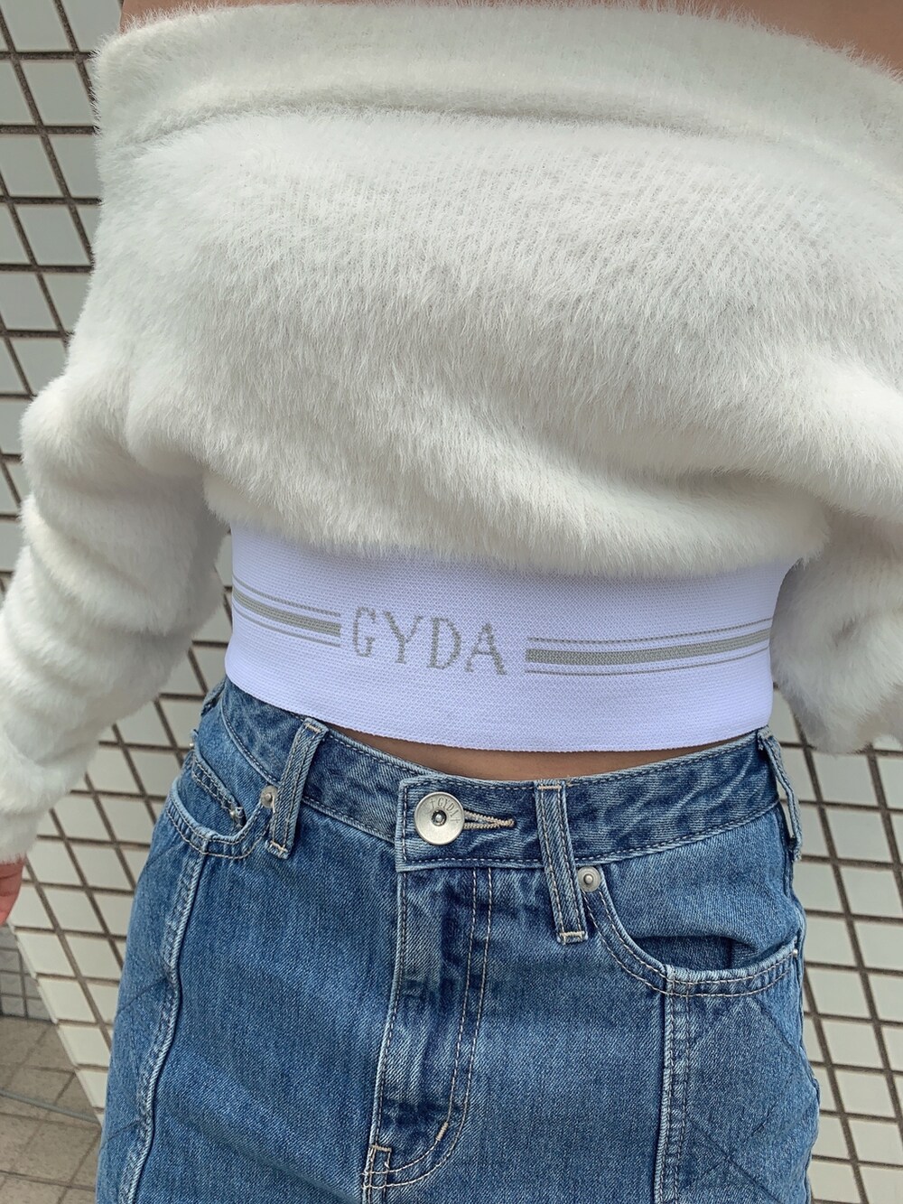 ブルー系のデニムスカート、ブラック系のブーツ、ホワイト系のニット/セーターを着用したレディースの秋コーディネートの6枚目の写真