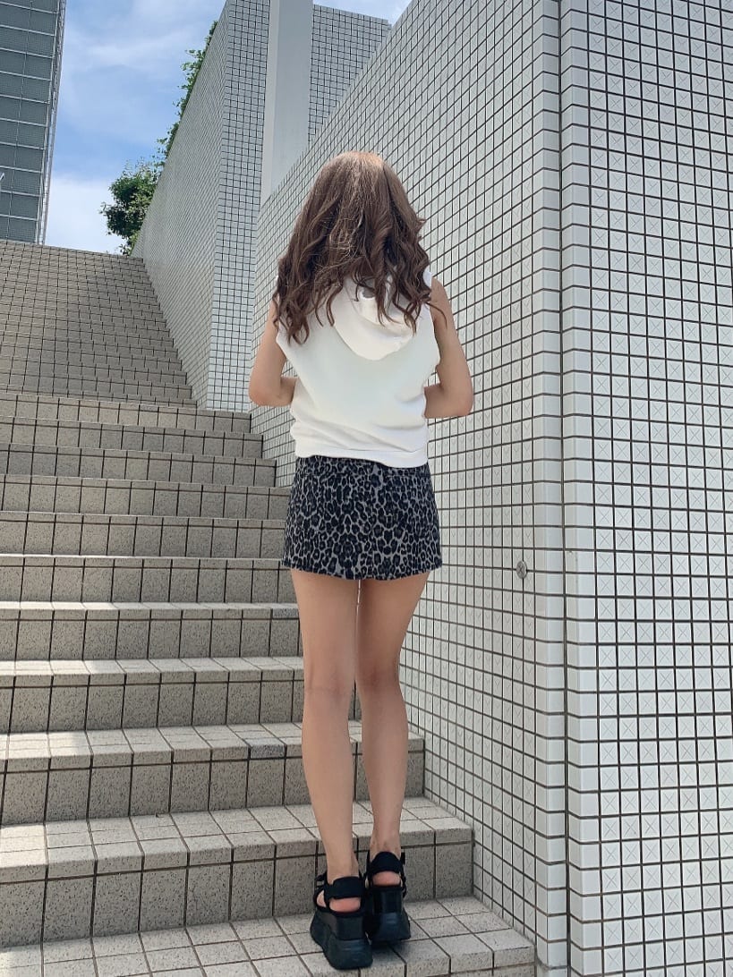 グレー系のスカート、ブラック系のサンダル、ホワイト系のタンクトップを着用したレディースの夏コーディネートの3枚目の写真