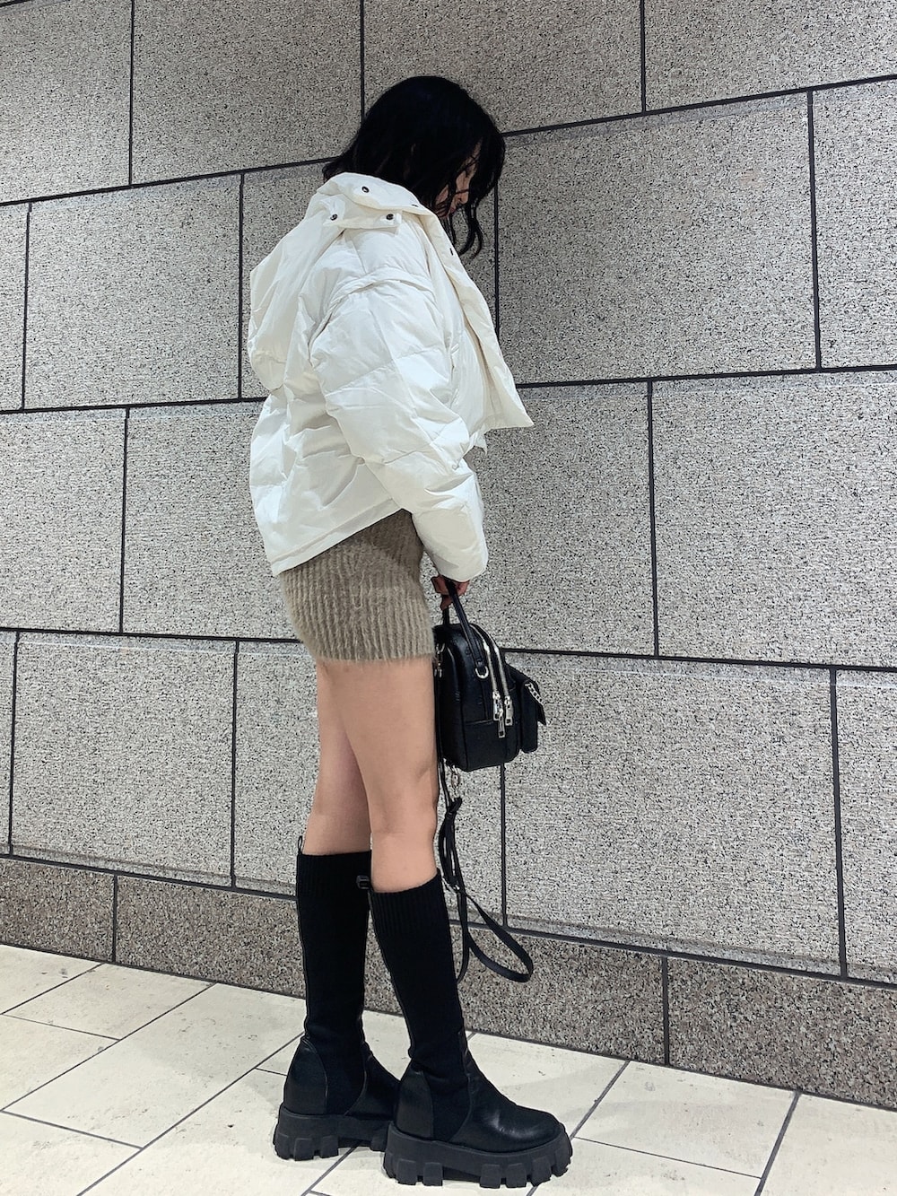 ブラック系のバックパック/リュック、ブラック系のブーツ、ホワイト系のダウンジャケット/コートを着用したレディースの冬コーディネートの2枚目の写真