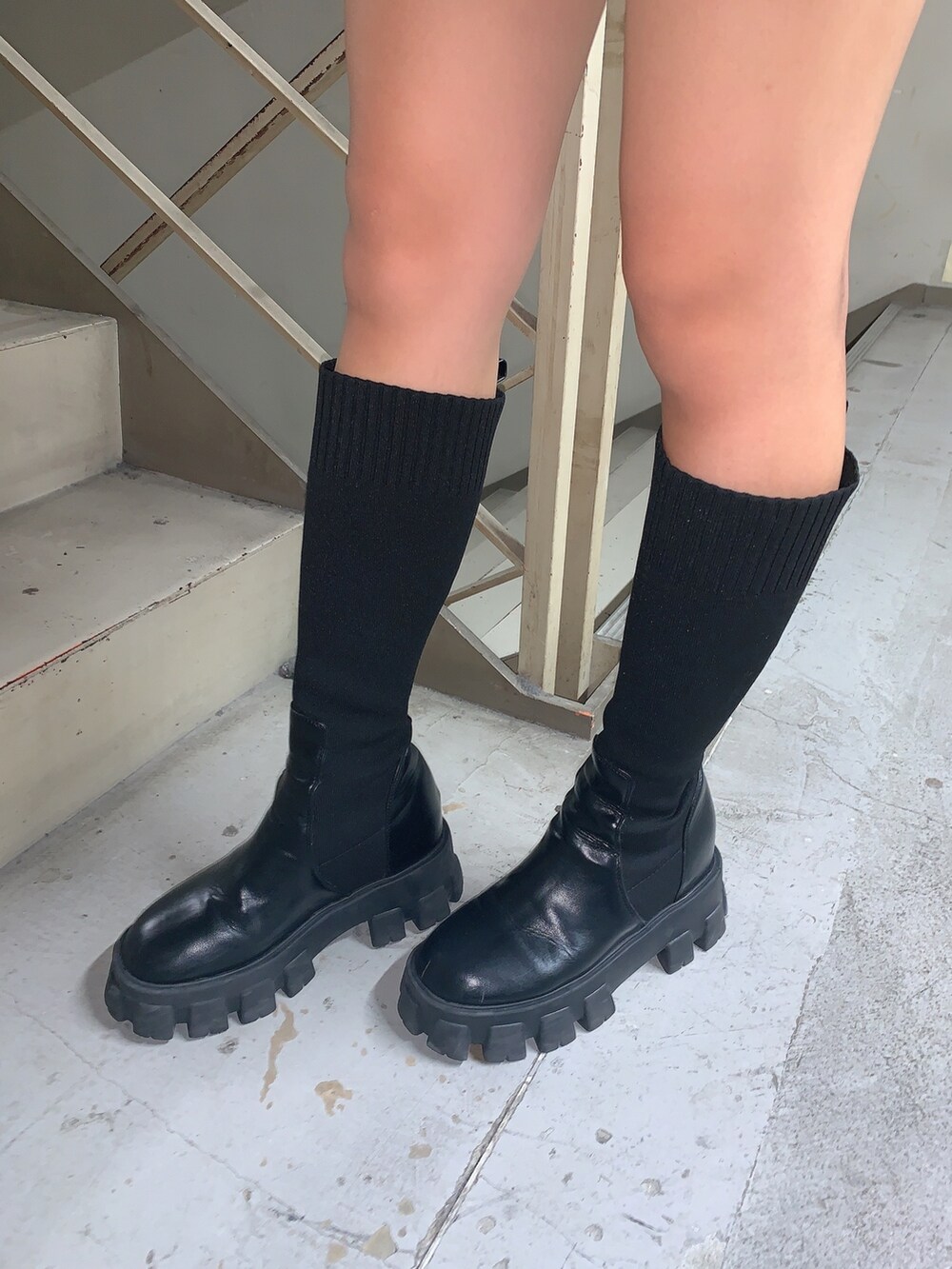 グレー系のニット/セーター、ブラック系のスカート、ブラック系のブーツを着用したレディースの秋コーディネートの7枚目の写真