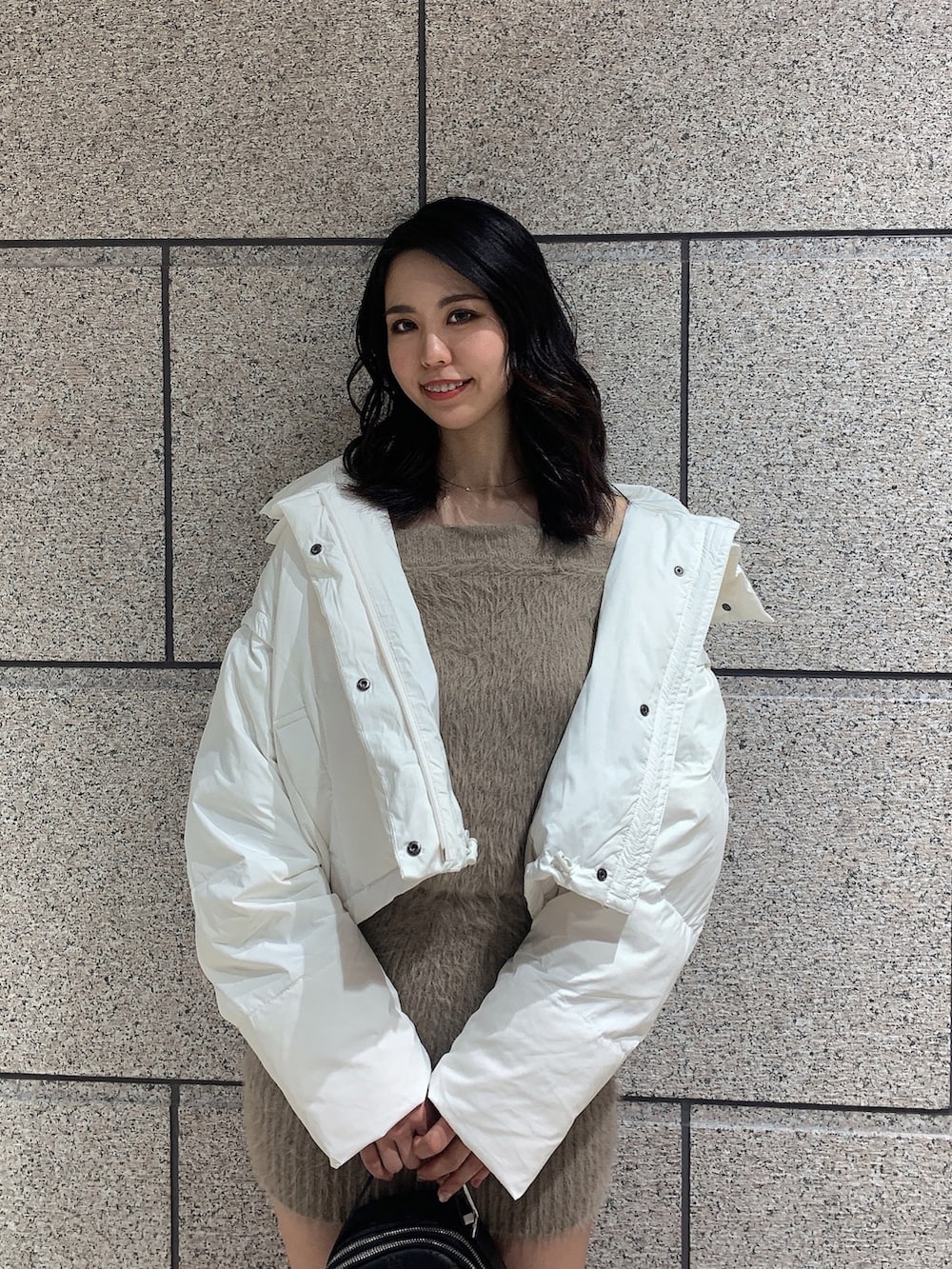 ブラック系のバックパック/リュック、ブラック系のブーツ、ホワイト系のダウンジャケット/コートを着用したレディースの冬コーディネートの3枚目の写真