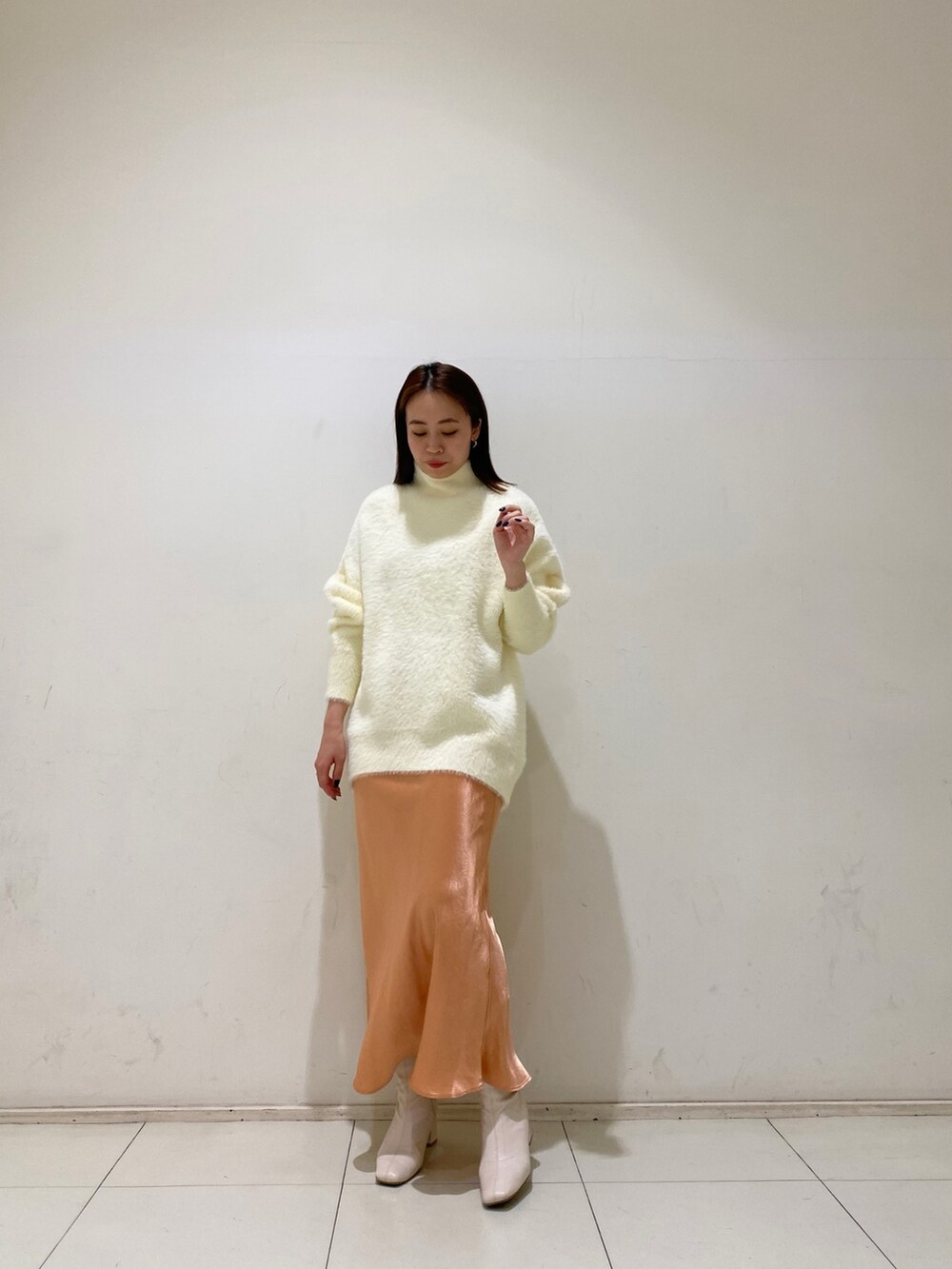 ホワイト系のニット/セーター、オレンジ系のスカートを着用したレディースの冬コーディネートの2枚目の写真