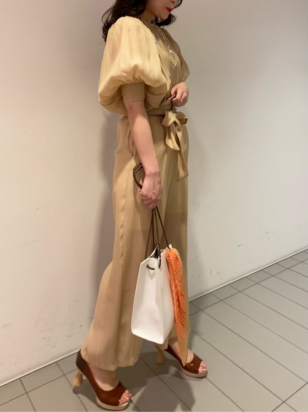 ブラウン系のパンプス、ホワイト系のハンドバッグ、ベージュ系のシャツ/ブラウスを着用したレディースの春コーディネートの3枚目の写真