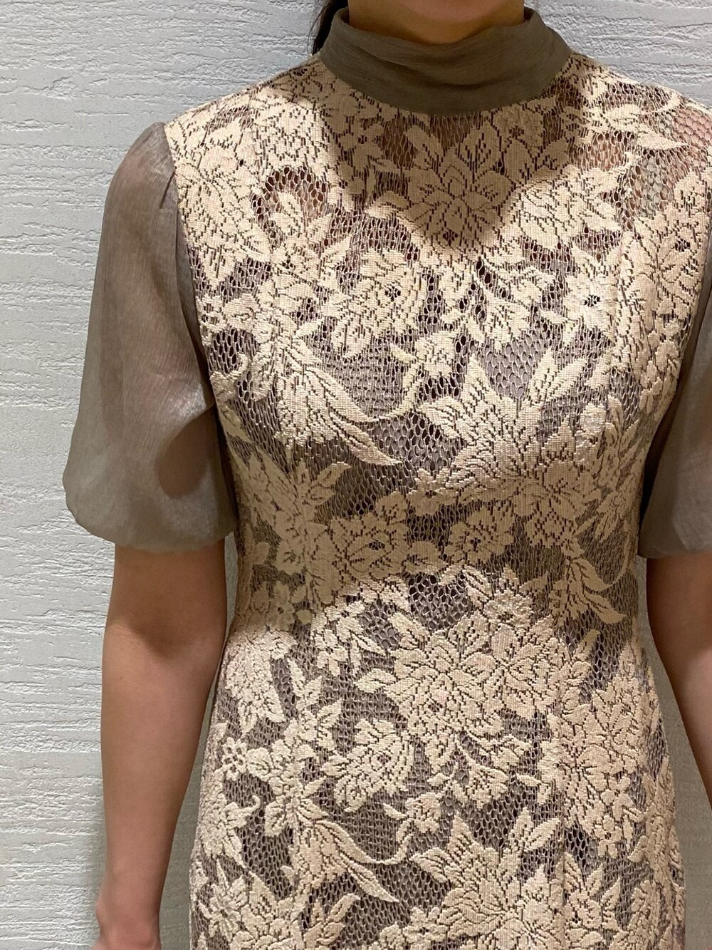 ベージュ系のドレス、ゴールド系のクラッチバッグ、ゴールド系のパンプスを着用したレディースの秋コーディネートの5枚目の写真