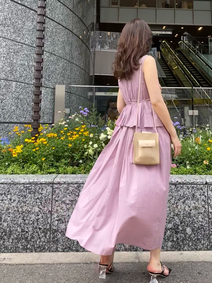 パープル系のワンピース、ブラック系のサンダル、ベージュ系のハンドバッグを着用したレディースの夏コーディネートの4枚目の写真