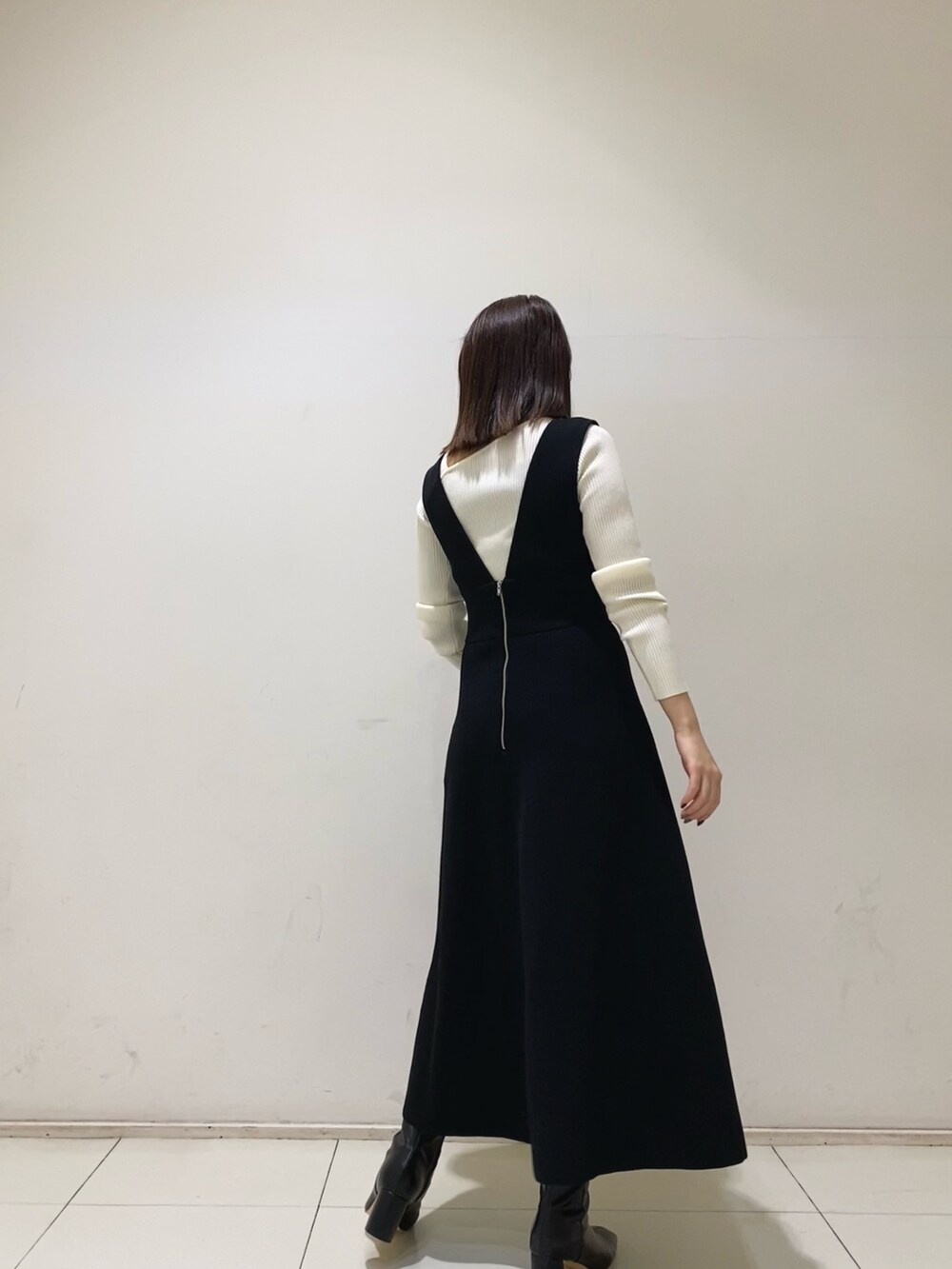 ブラック系のジャンパースカート、ホワイト系のニット/セーターを着用したレディースの秋コーディネートの3枚目の写真