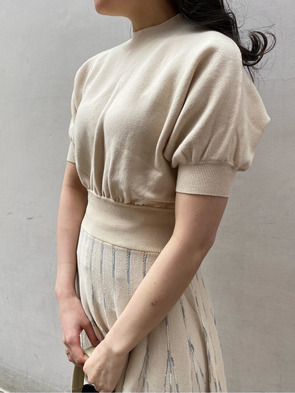 ベージュ系のトレンチコート、ホワイト系のワンピース、ホワイト系のハンドバッグを着用したレディースの春コーディネートの3枚目の写真