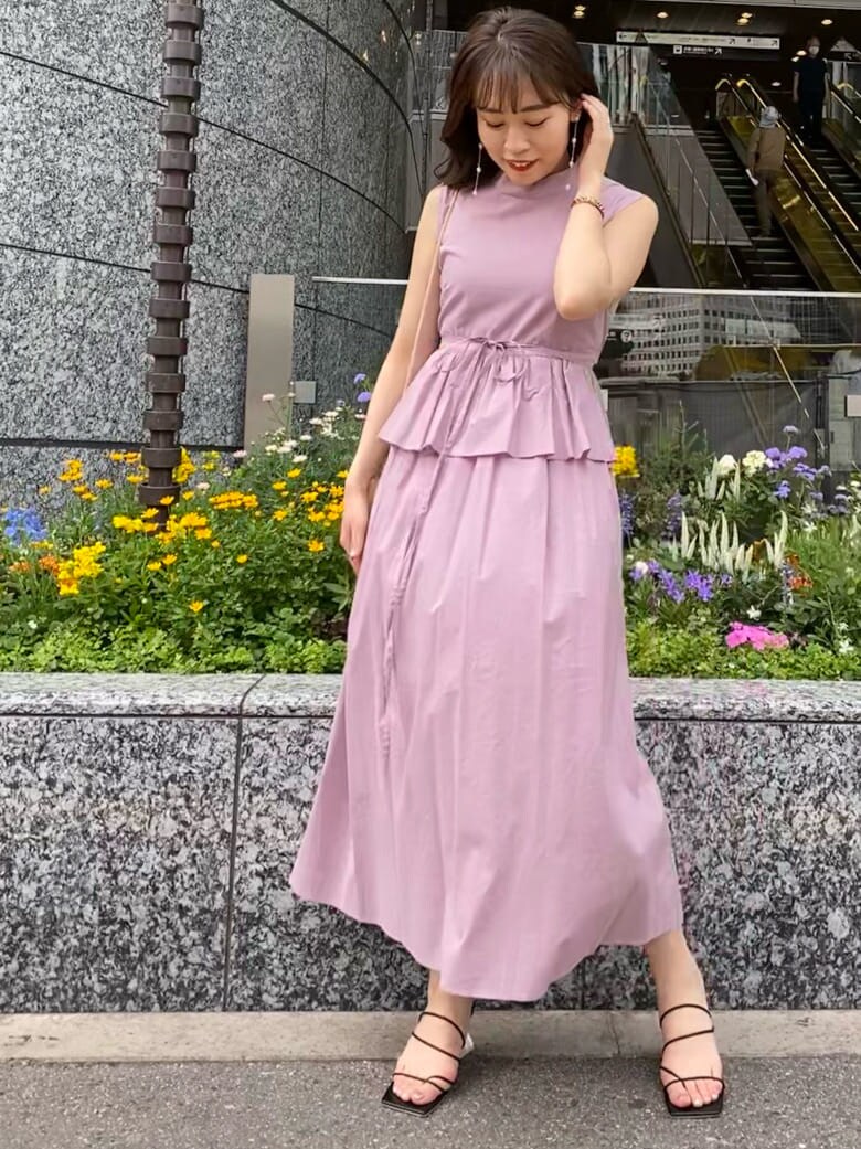 パープル系のワンピース、ブラック系のサンダル、ベージュ系のハンドバッグを着用したレディースの夏コーディネートの3枚目の写真