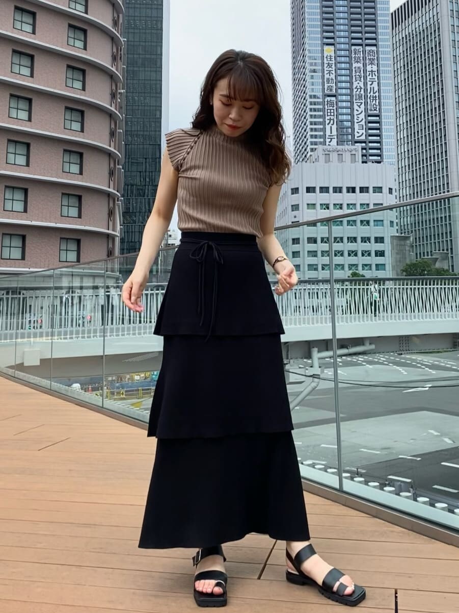 ブラック系のスカート、ブラック系のサンダル、ベージュ系のニット/セーターを着用したレディースの夏コーディネートの4枚目の写真