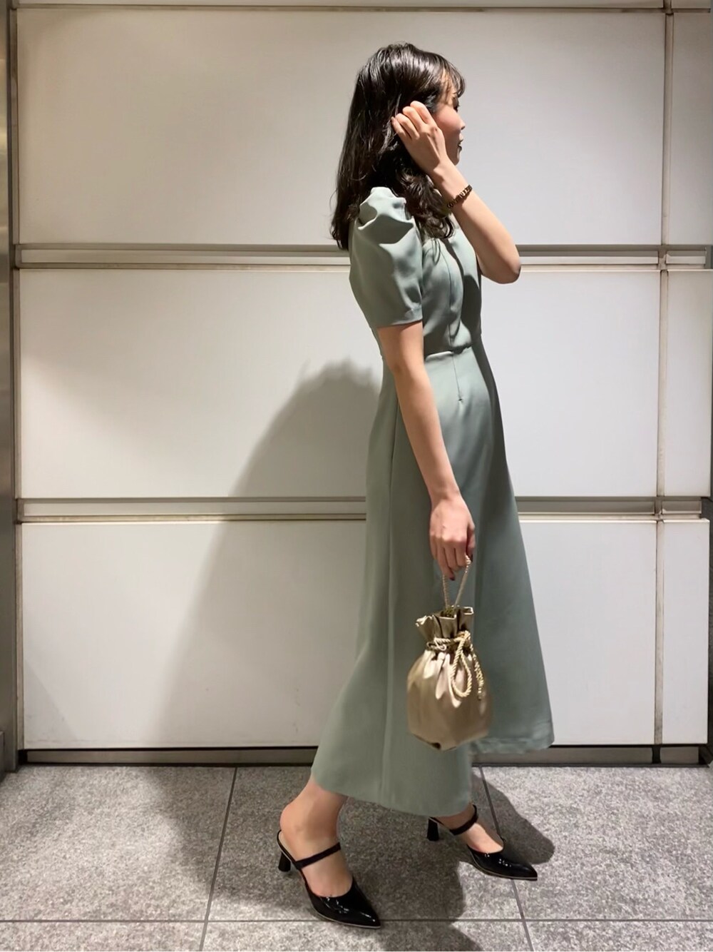 ブラック系のその他シューズ、グリーン系のドレス、ゴールド系のハンドバッグを着用したレディースの春コーディネートの3枚目の写真